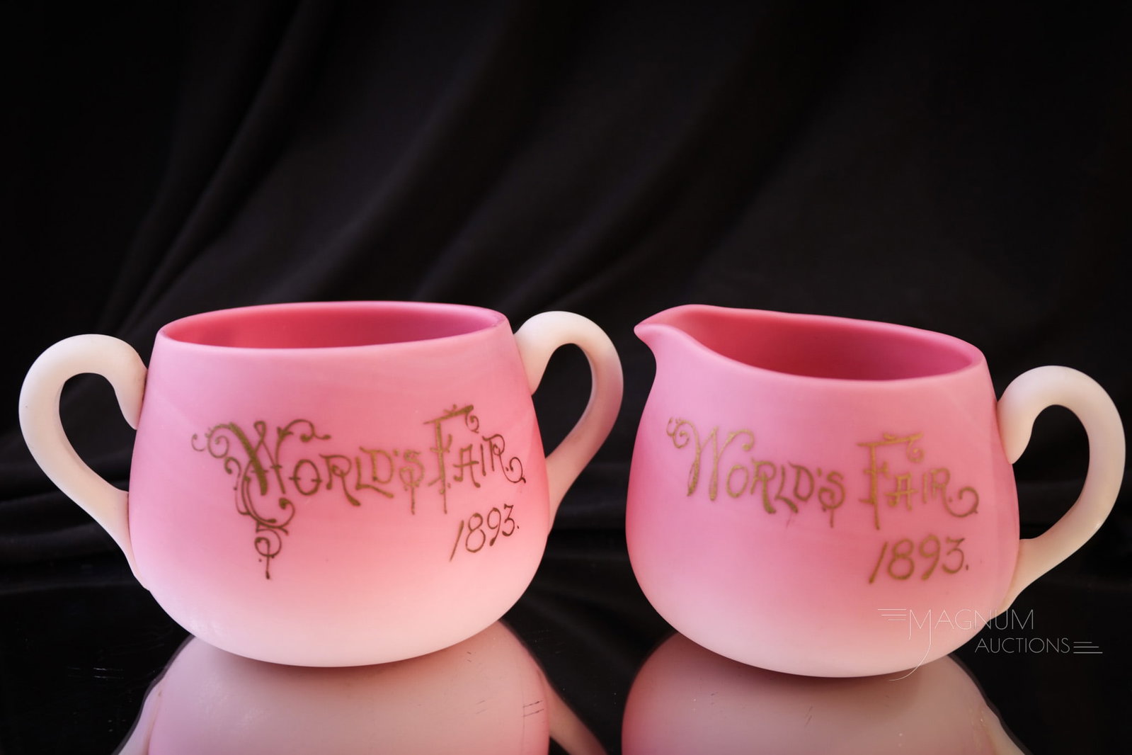 Libbey New England Peachblow ""1893 World's Fair" Victorian Glass Creamer & Sugar: Two superb examples of Libbey New England Peachblow satin glass with the "1893 World's Fair" in gilt décor. In this lot we have a matching creamer and sugar bowl. Tallest measures 2 3/4".