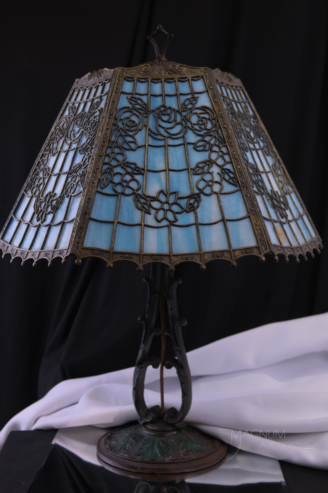 Antique Filigree Slag Panel Table Lamp: A fine antique blue slag glass panel lamp with a filigree overlay. Complete on an ornate cast metal base. Lamp meausures 22" tall.
