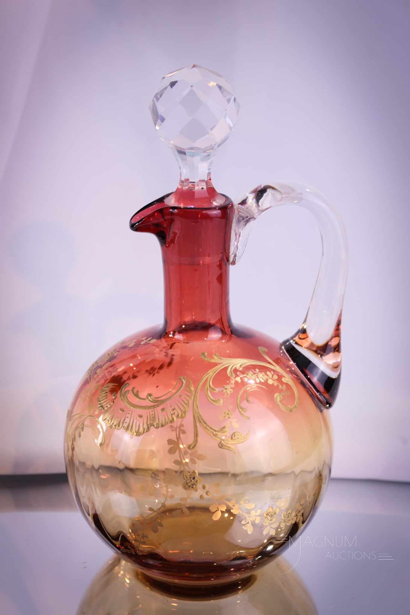 Moser Amberina Gilt Decorated Victorian Glass Cruet: Beautiful shaded coloring is found on this amberina attributed to Moser art glass cruet. Cruet is complete with clear applied handle and cut faceted stopper. Piece measures 8" tall.