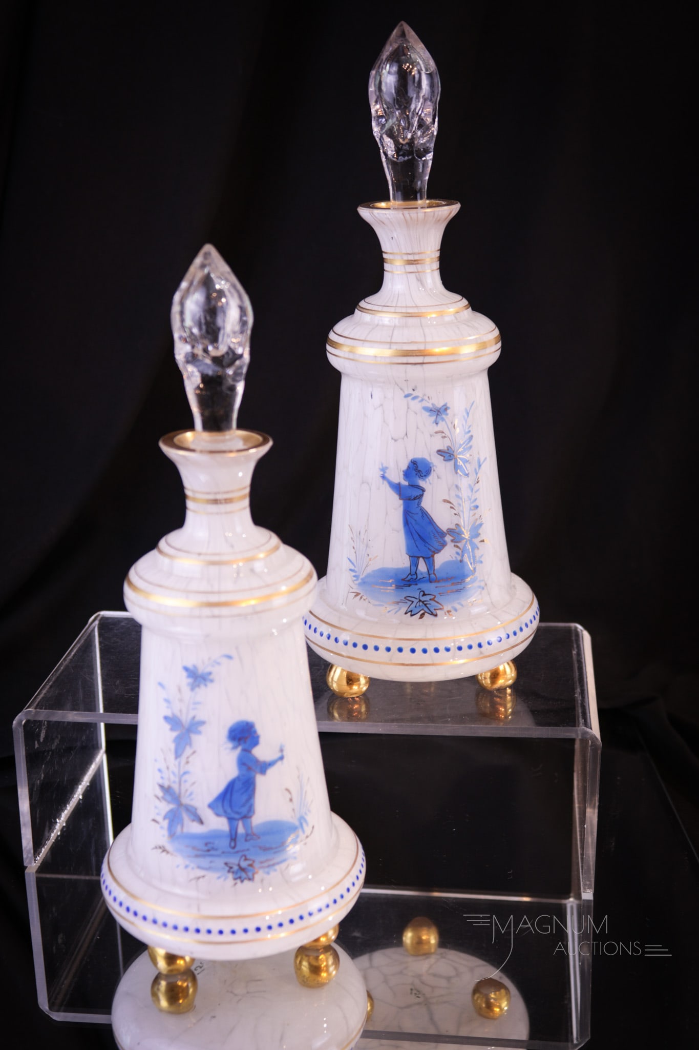 Pair Victorian Cased Spatter Mary Gregory Cologne Perfume Bottles: Pair of Victorian art cased spatter glass cologne bottles. Each with applied glass ball feet. Each also features opposing decoration in blue Mary Gregory decoration. Each measures 9" tall.