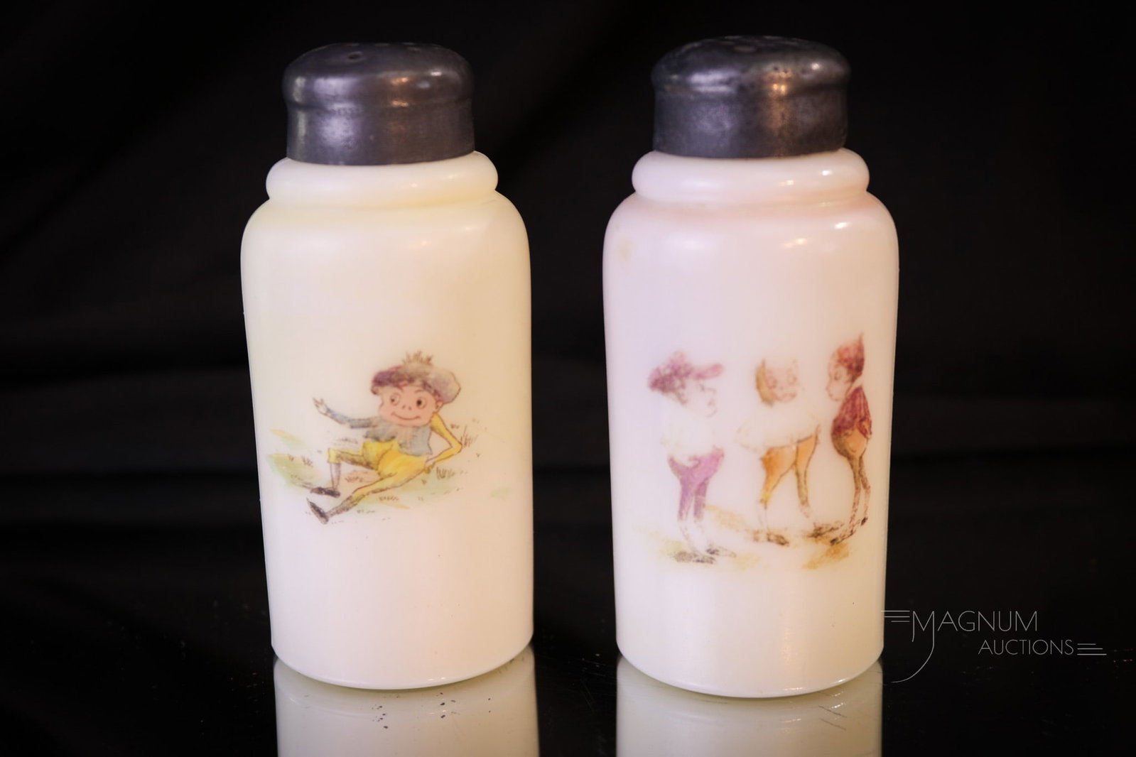 Pair Victorian Palmer Cox Brownies Salt Shakers: Two fine Victorian opal glass salt shakers decorated with Palmer Cox Brownies decoration. Each measures 3 3/4" tall. One has slight wear to decoration as shown.