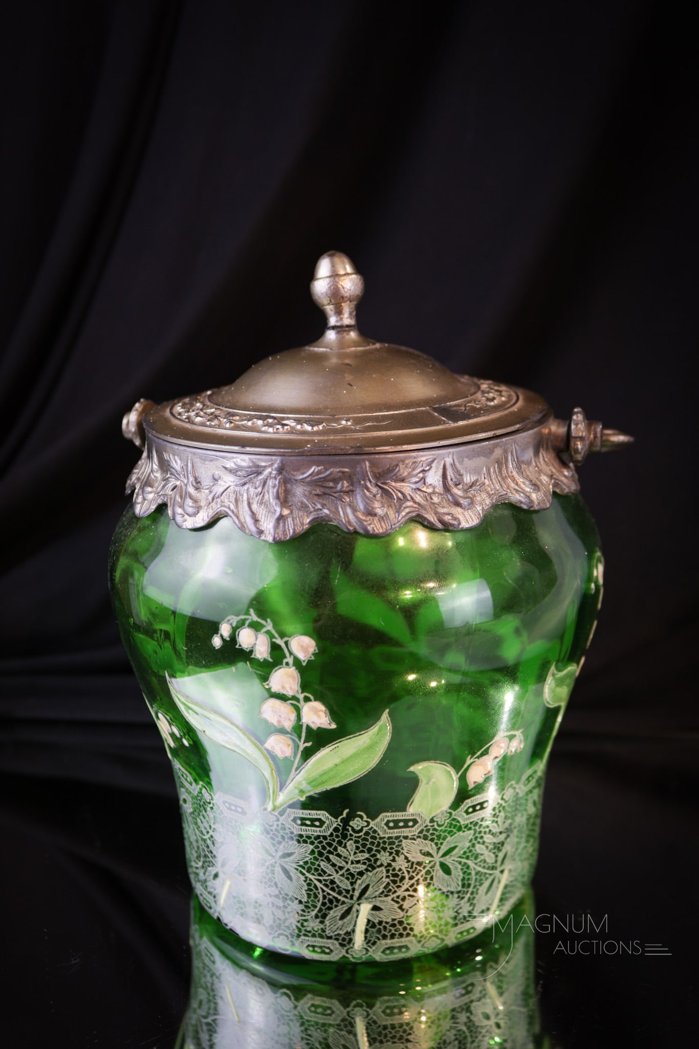 Mont Joye Enameled Glass Lily of the Valley Biscuit Jar: A beatufiul piece of art glass attributed to Mont Joye. This biscuit jar is in emerald green with enameled lily of the valley flowers. Original mountings. Piece measures 7 1/2" tall.