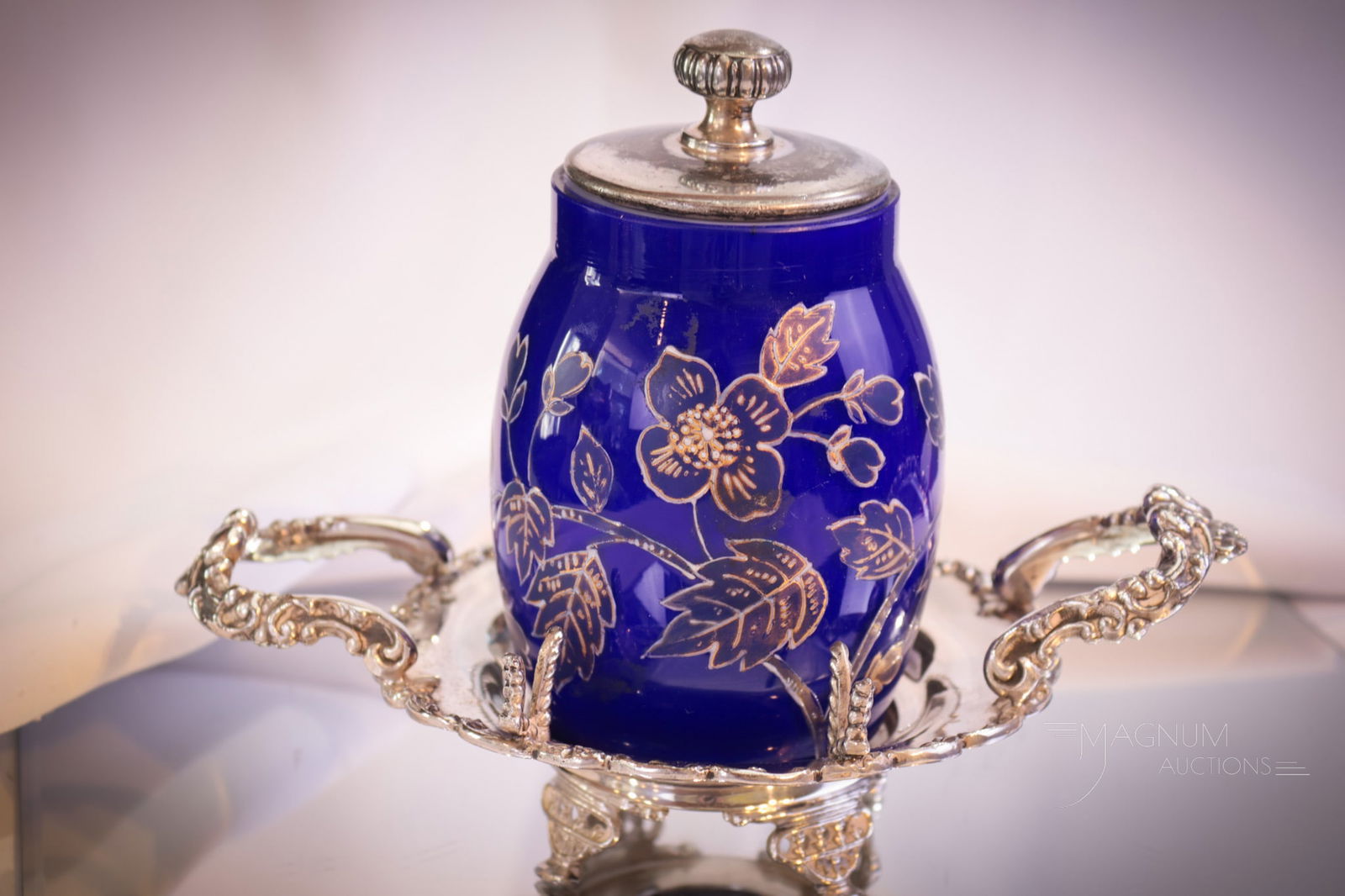 Hawthorne Silverplate Victorian Cobalt Blue Cased Enameled Pickle Castor: A charming find in this Victorian signed, "Hawthorne" silverplate pickle castor frame complete with a cobalt blue cased glass jar. The jar is decorated with florals. Complete this piece measures 6 1/4