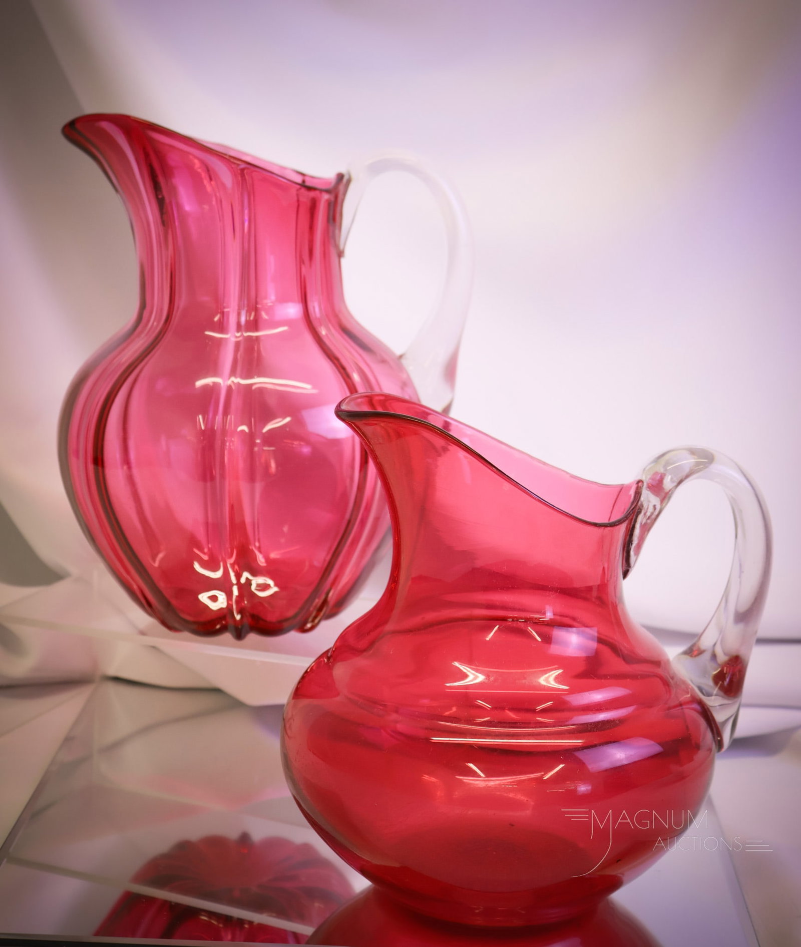 2 pc Lot Hobbs Victorian Cranberry Glass Water Pitchers: Two unique finds in Victorian Hobbs glass water pitchers make up this offering. The first is a bulge base example. The second is a ribbed for pleasure example. The largest of the two measures 9 1/2"" 