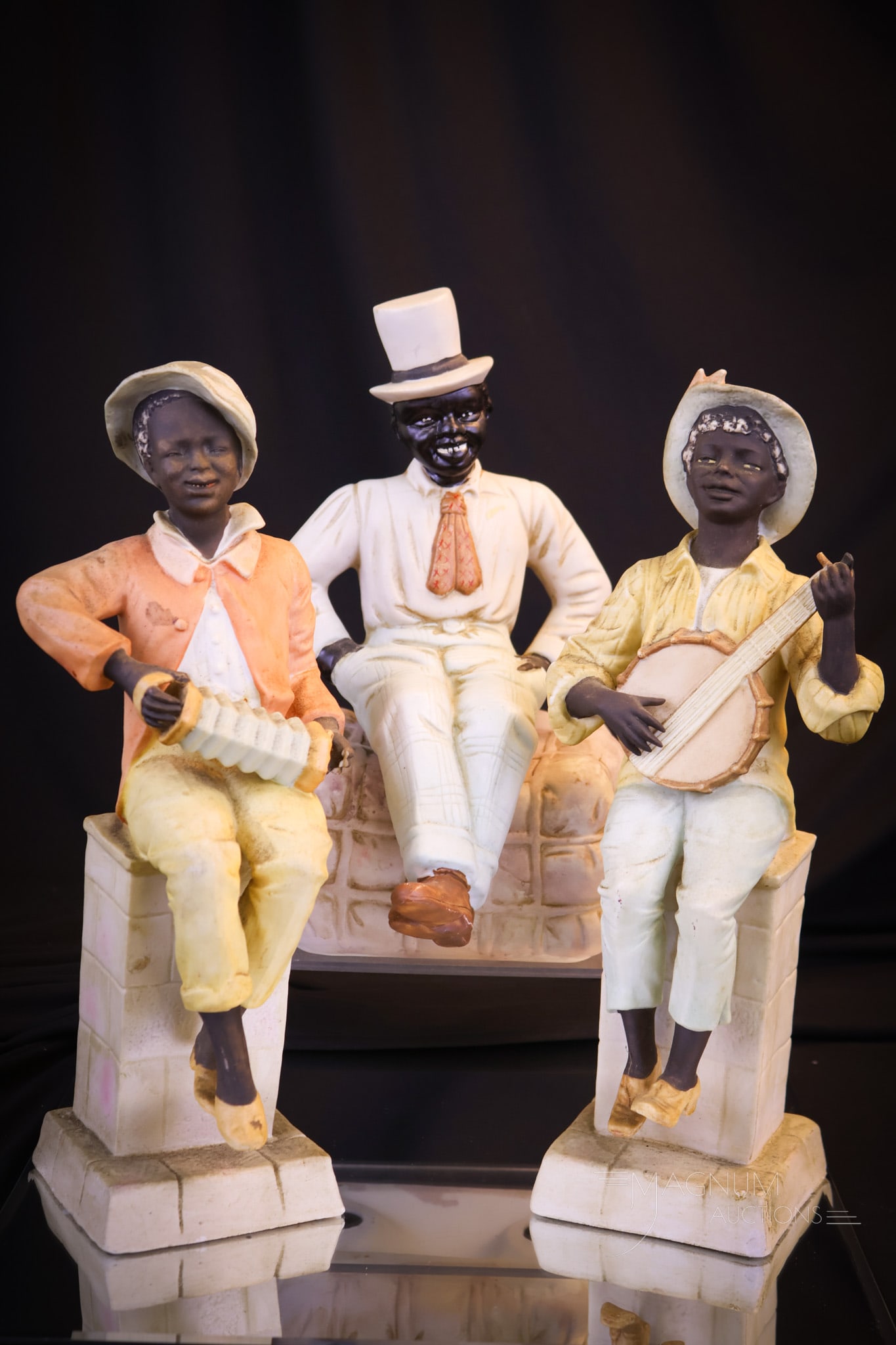 3 pc Lot Black Memorabilia Bisque Porcelain: Three charming examples of black memorabilia. This lot includes two musicians. One is playing an accordion. The other is playing a banjo. The third figure is a happy black man with top hat seated on a