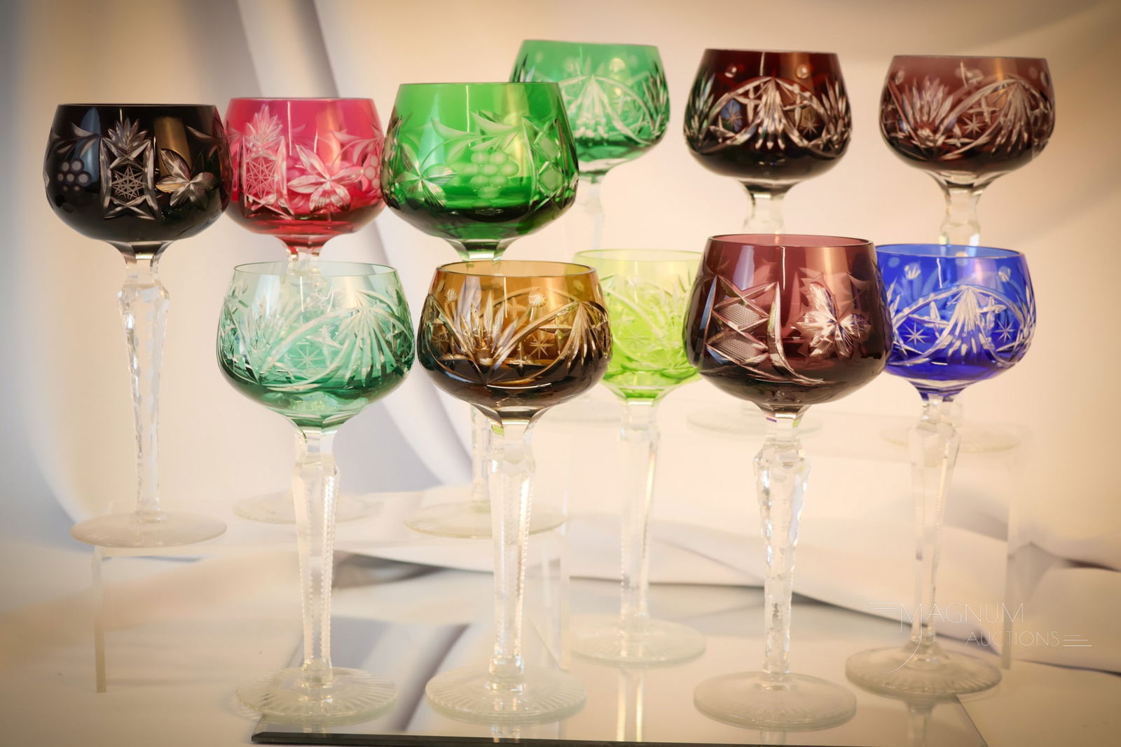 11 pc Lot Colored Cut to Clear Wine Goblets: A nice array of colors and patterns are presented in this eleven-piece lot for your bidding pleasure. This lot includes four that have grape motif engraving. The tallest measures 8"". Shipping: At ch