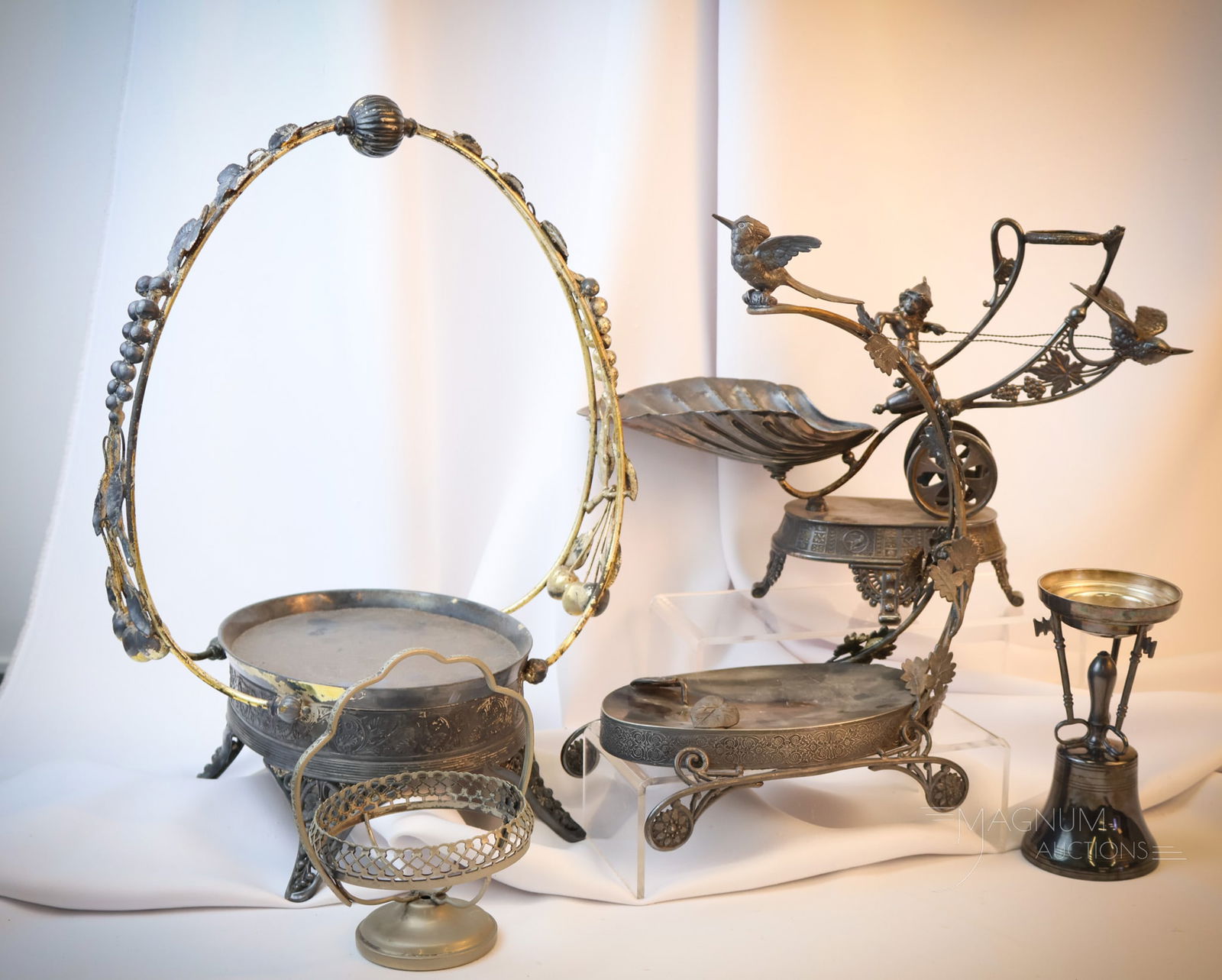 5 pc Lot Victorian Silverplate Holders: Five select Victorian silverplate holders are featured in this generous lot. There are two Bride's bowl frames, including one with a bird on the top. A figural centerpiece that takes a horn that inclu