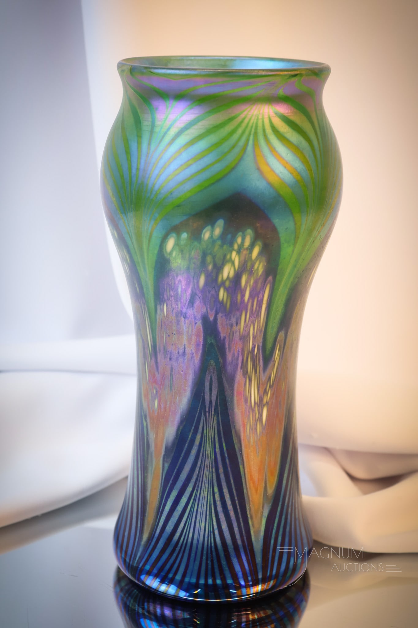 Art Glass Vase in the manner of Tiffany/ Loetz: A beautiful art glass vase in the style and coloring of Tiffany or Loetz. This vase bears a spurious signature on the base. The vase has a beautiful iridescent finish and coloring. The vase measures 1