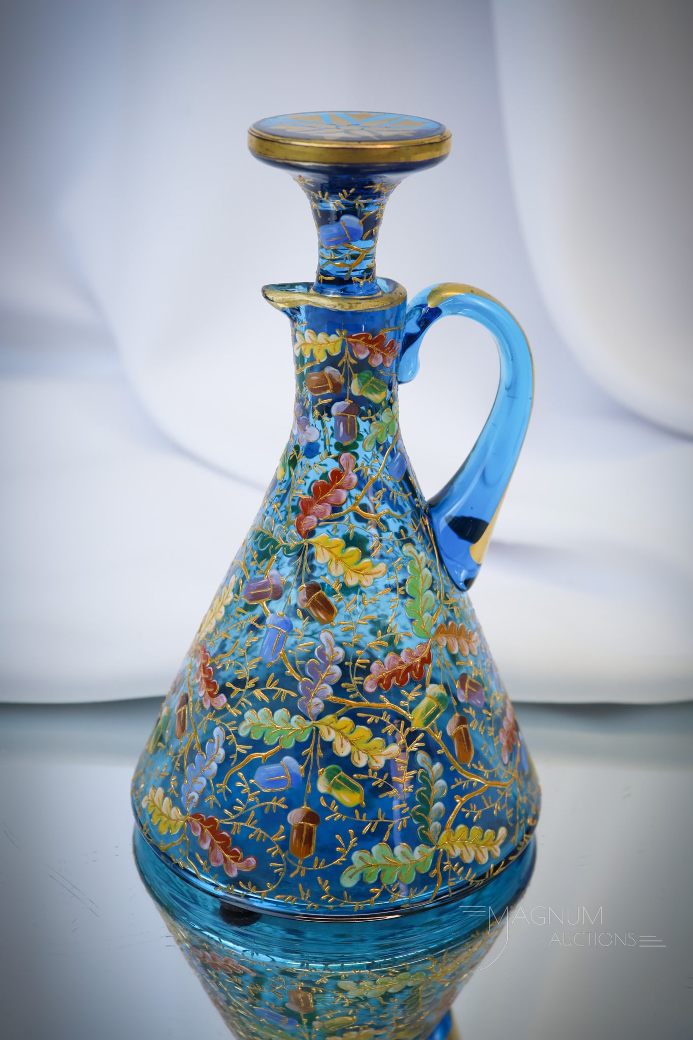 Rare Victorian Prussian Blue Acorn Enameled Gilt Glass Cruet: A rare find in Victorian Moser glass. This is a Prussian blue cruet. It is elaborately decorated with colorful oak leaves and applied acorns. The cruet retains the original matching stopper. The cruet