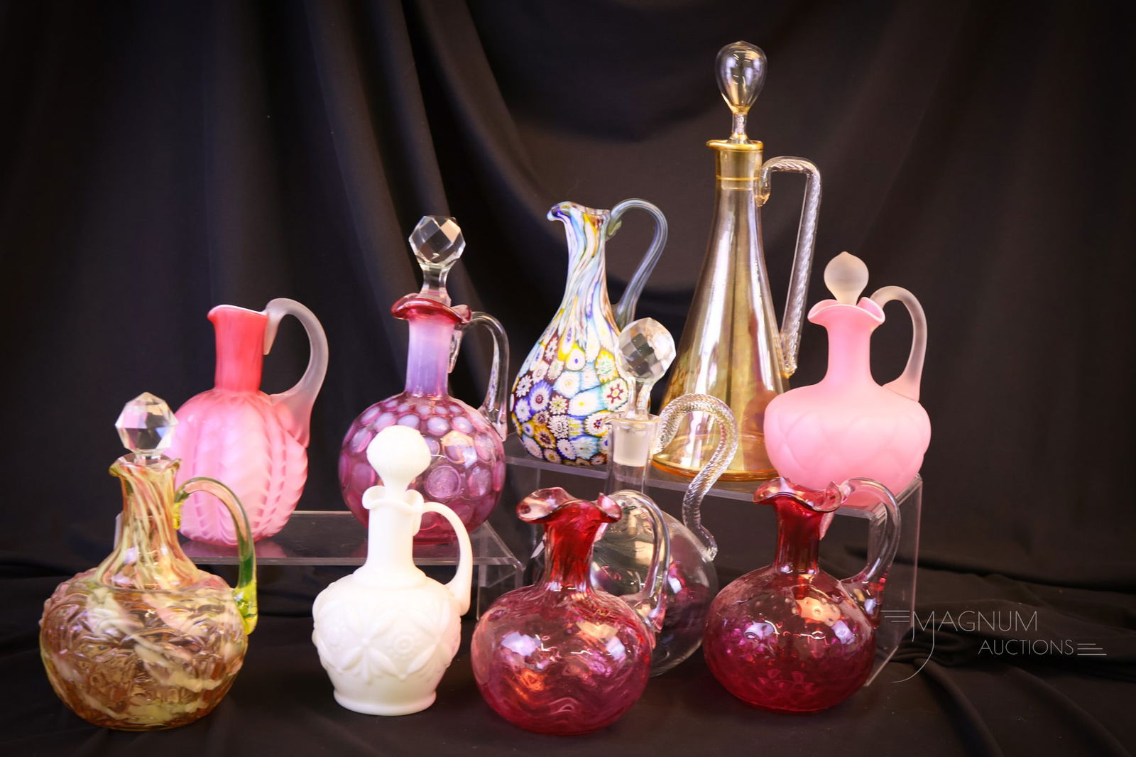 10 pc Lot Magnummania Cruet Lot: Ten great finds in this Magnummania lot cruets. This lot includes two cranberry cruets attributed to Phoenix. A Northwood Leaf Mold and beaded Crosstie. A millefiori and amber iridescent. A consolidat