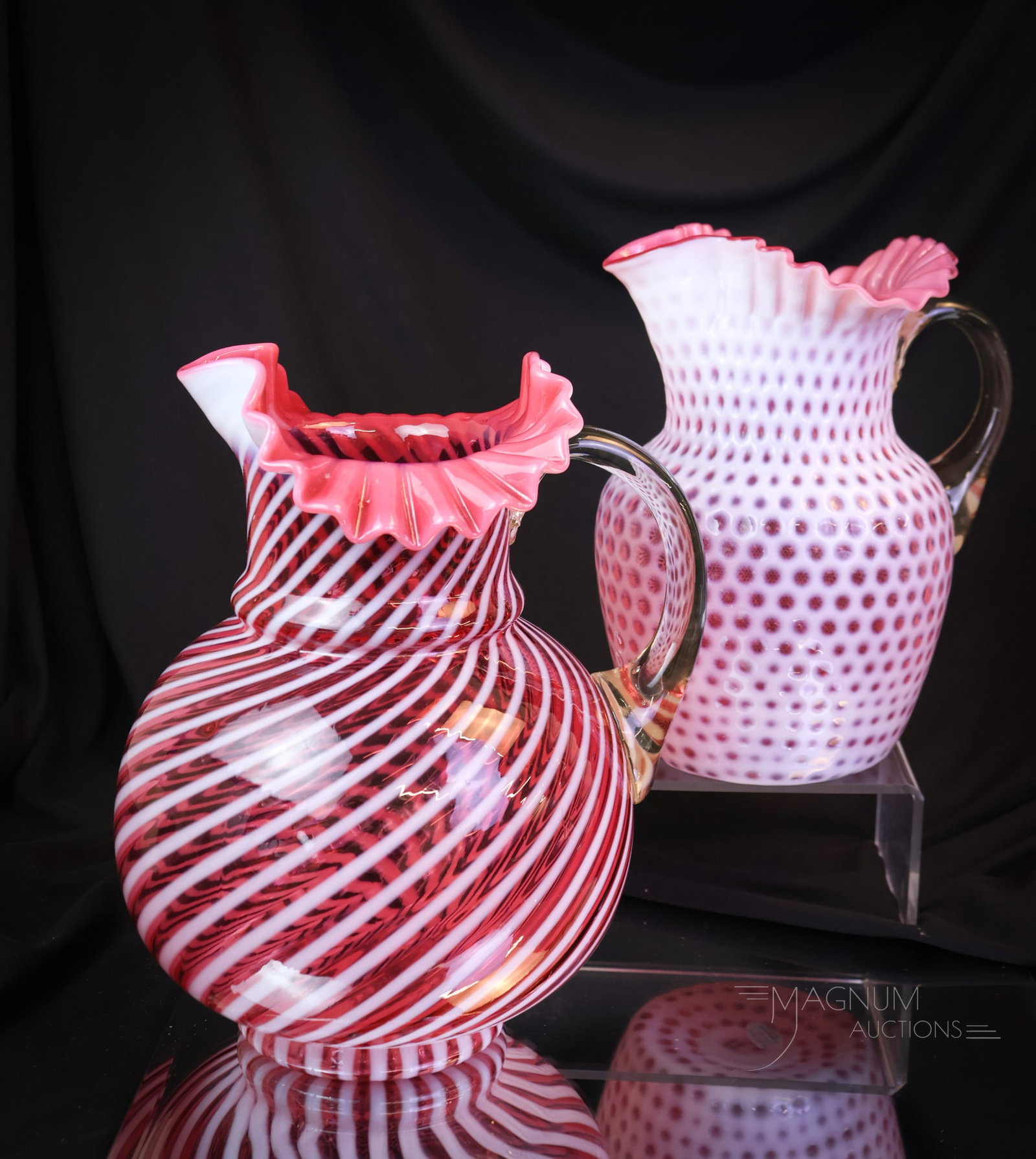 2 pc Lot Cranberry Opalescent Victorian Water Pitchers: Two beautiful Victorian glass opalescent water pitchers in cranberry opalescent glass. One in the spiral swirl pattern. The other in a Windows pattern. The tallest measures 10". SHIPPING NOTICE: If yo