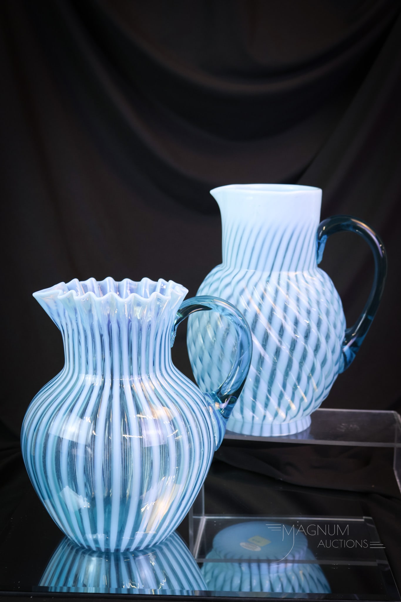 2 pc Lot Blue Opalescent Victorian Glass Water Pitchers: Two beautiful and great examples of blue opalescent Victorian glass water pitchers. This lot offers a Reverse Swirl example along with a Stripe example. The tallest of the two measures 9 1/2". SHIPPIN