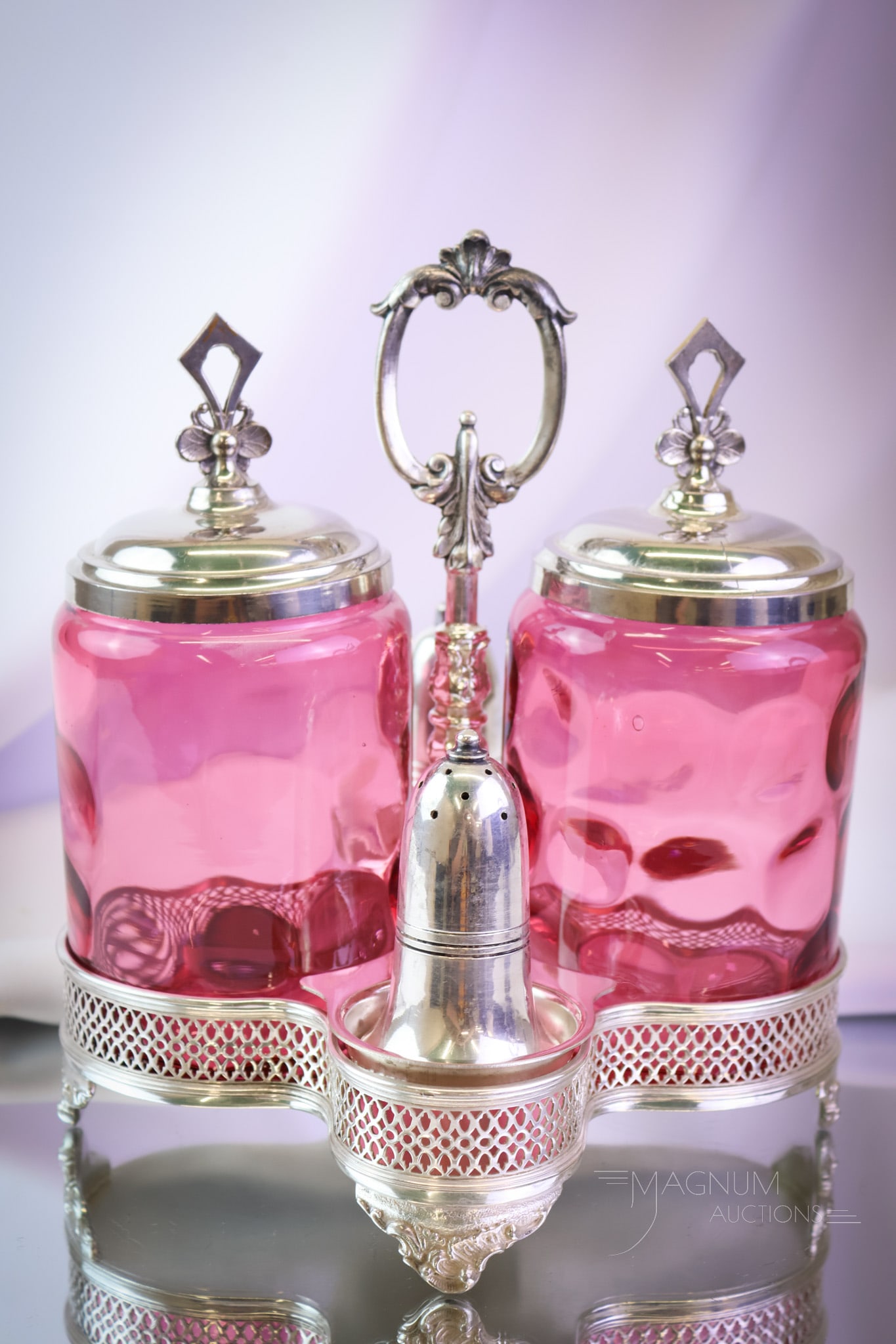 English Hallmarked Silverplate Cranberry Glass Condiment Pickle Castor: A fine piece of Victoriana. This is a Victorian castor condiment. It's complete with two cranberry glass pickle jars and a shaker set in a hallmarked English silverplate holder. This piece measures 9"