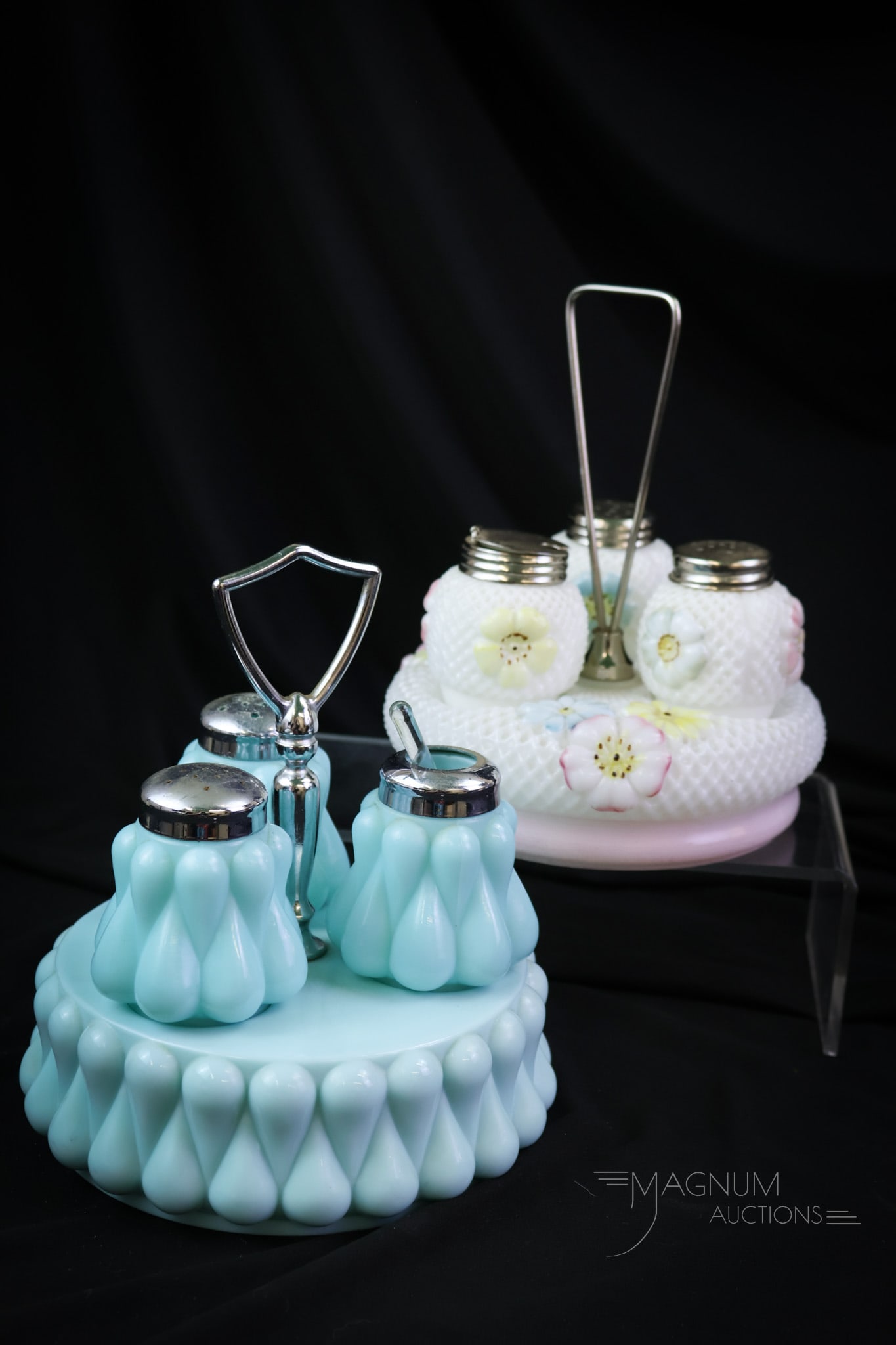 2 pc Lot Victorian & More Condiment Shaker Sets: Two nice finds in glass shaker sets. One is a cosmos set complete in holder. The second is a turquoise teardrop pattern. The tallest measures 7". Roughness is noted around the base of the stand of the