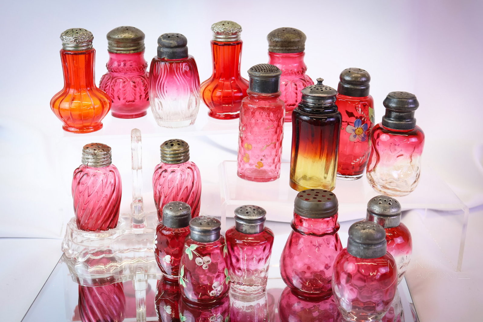17 pc Lot Victorian Cranberry Amberina Enameled Glass Victorian Salt Shakers: A fine grouping of cranberry, rubina, pigeon blood, and amberina Victorian glass salt shakers. This lot includes various patterns and some with decoration. One pair is in a glass holder. The tallest m