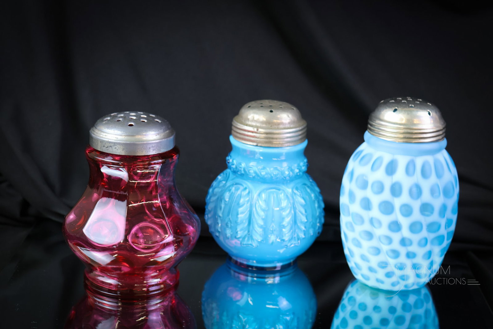 3 pc Lot Victorian Glass Northwood Opalescent Cranberry Sugar Shakers: A lot of three unique form and pattern Victorian glass sugar shakers. There is a Northwood Leaf Umbrella in blue cased. A Cranberry Inverted Thumbprint pattern. Finally, a Hobbs blue opalescent satin 