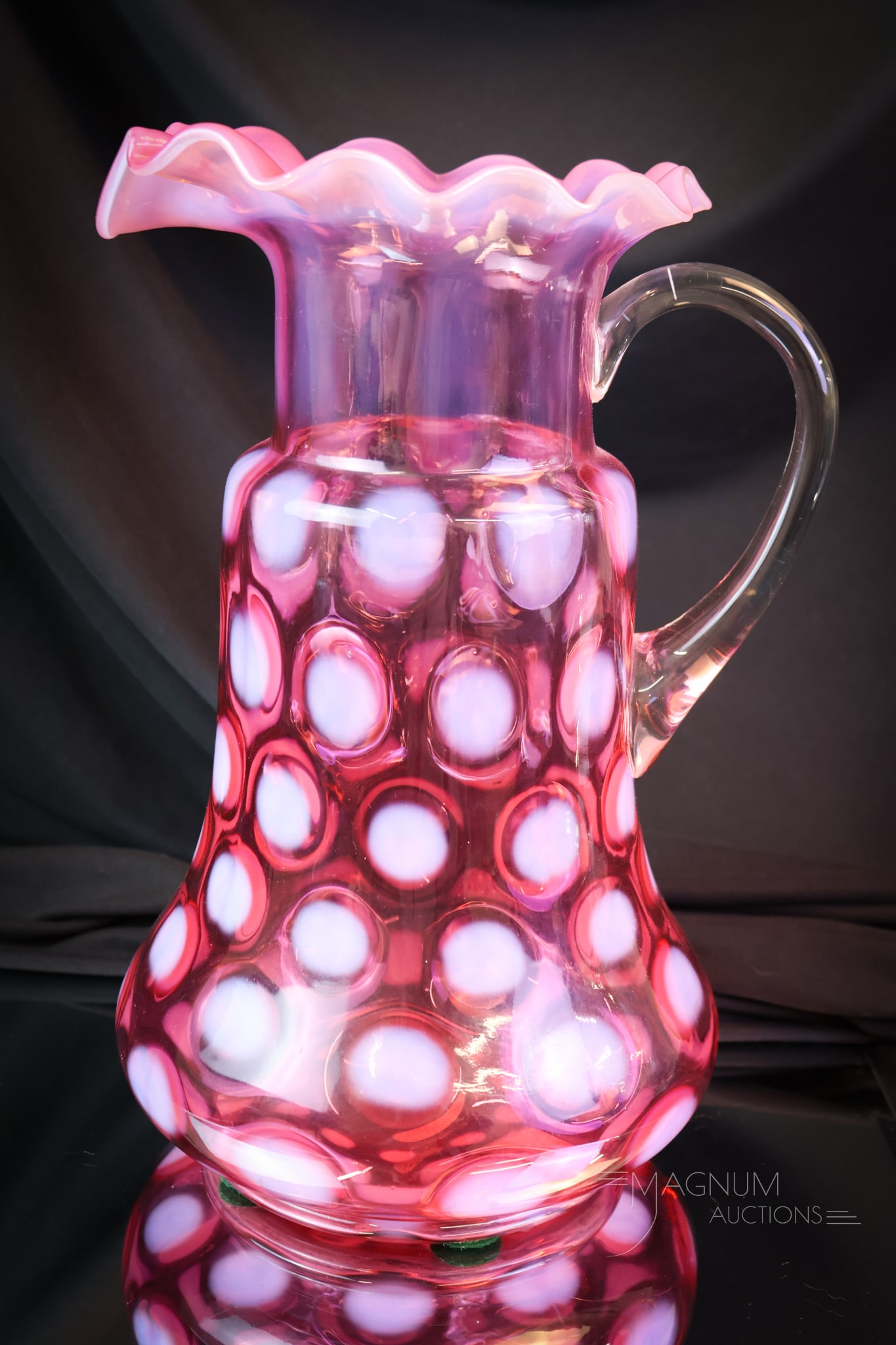 Scarce Dugan Diamond Victorian Cranberry Opalescent Water Pitcher: A scarce find in Dugan/Diamond Victorian glass. This is a tankard pitcher in cranberry opalescent coin spot pattern. This excellent example features a ruffled top rim. The pitcher measures 11 1/2" tal