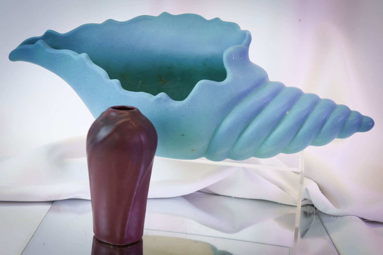 2 pc Lot Van Briggle Art Pottery Mulberry & More: Two unique forms of Van Briggle art pottery. The first is a conch shell vase in turquoise. The second is a Mulberry matte glaze cabinet vase with an embossed flower. The tallest measures 5" by 16". SH