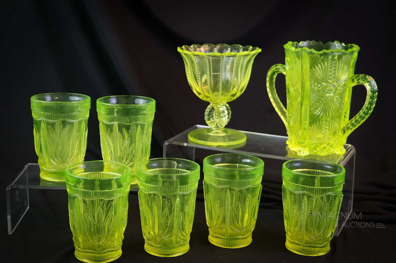 8 pc Lot Vaseline Uranium Glass: Eight sparkling pieces of uranium-rich vaseline glass. This lot includes six Cactus pattern tumblers. There is also a thistle celery vase. The last piece is a Beaded compote. The tallest measures 4 1/