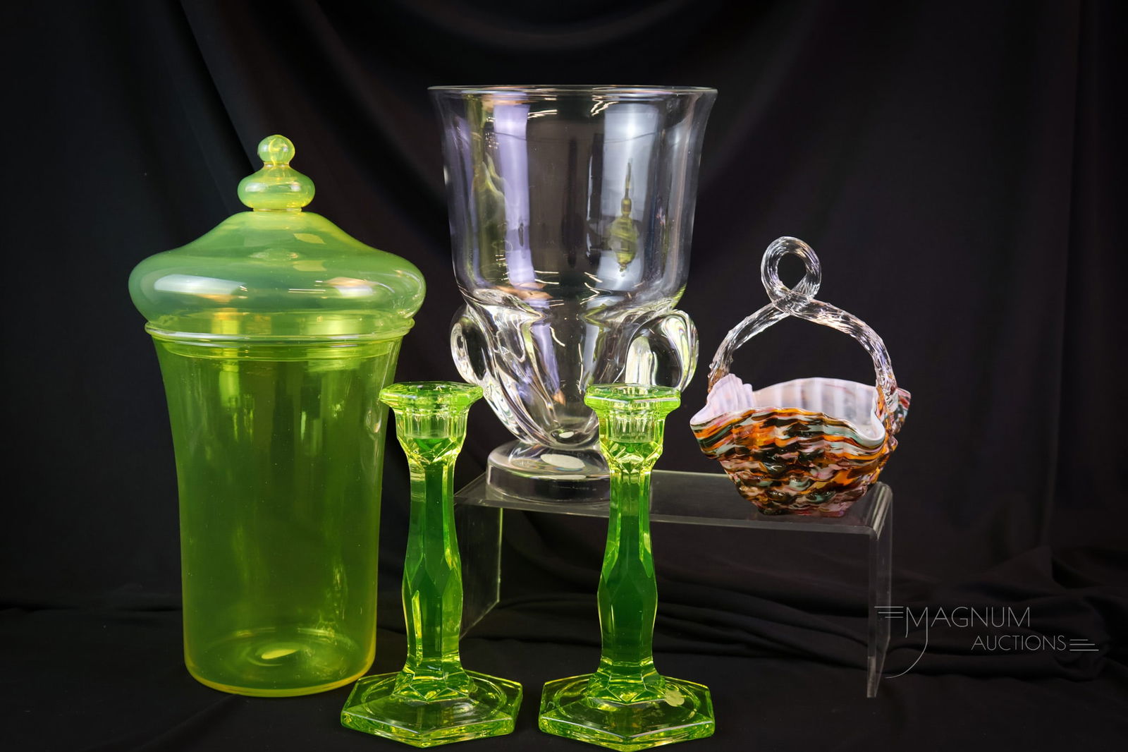 5 pc Lot Collectible Goodness in Glass Vaseline Steuben & More: Five delights in collectible glass. This lot offers a pair of vaseline uranium-rich candlesticks, a splatter glass basket, a signed Steuben crystal vase and a yellow-covered jar. The tallest measures