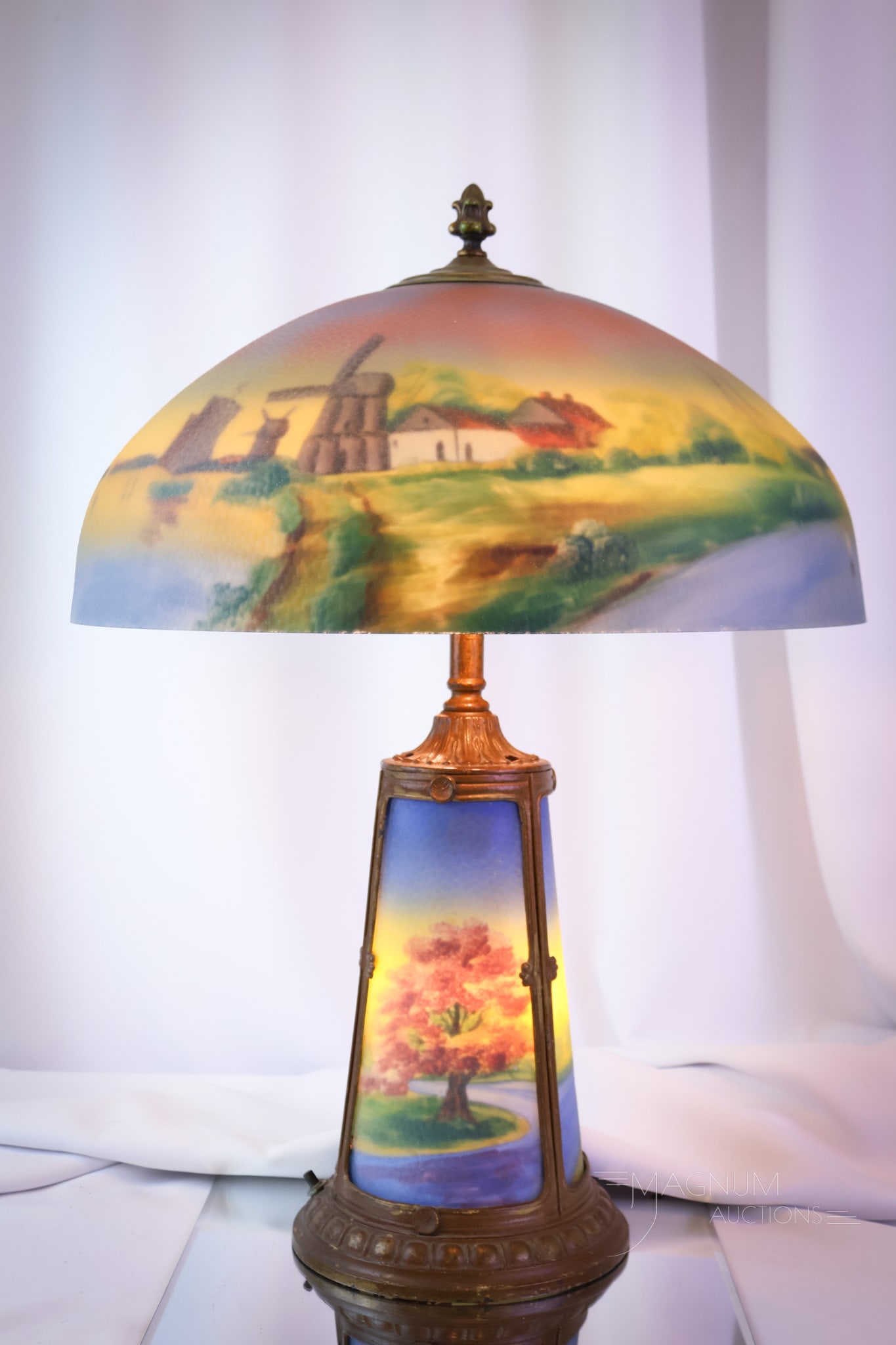 Pittsburgh Reverse Painted Antique Table Lamp: A vividly colored antique Pittsburgh reverse-painted table lamp. This colorful example features a windmill and a scenic landscape. The base is lit as well on this beautiful lamp. The lamp measures 23"