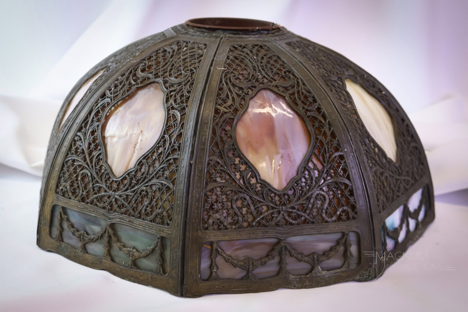 Miller Antique Slag Overlay Table Lamp Shade: A beautiful original condition attributed to Miller slag overlay glass antique table lamp shade. This fine bent panel shade features caramel and blue slag. The shade is covered in intricate filigree. 