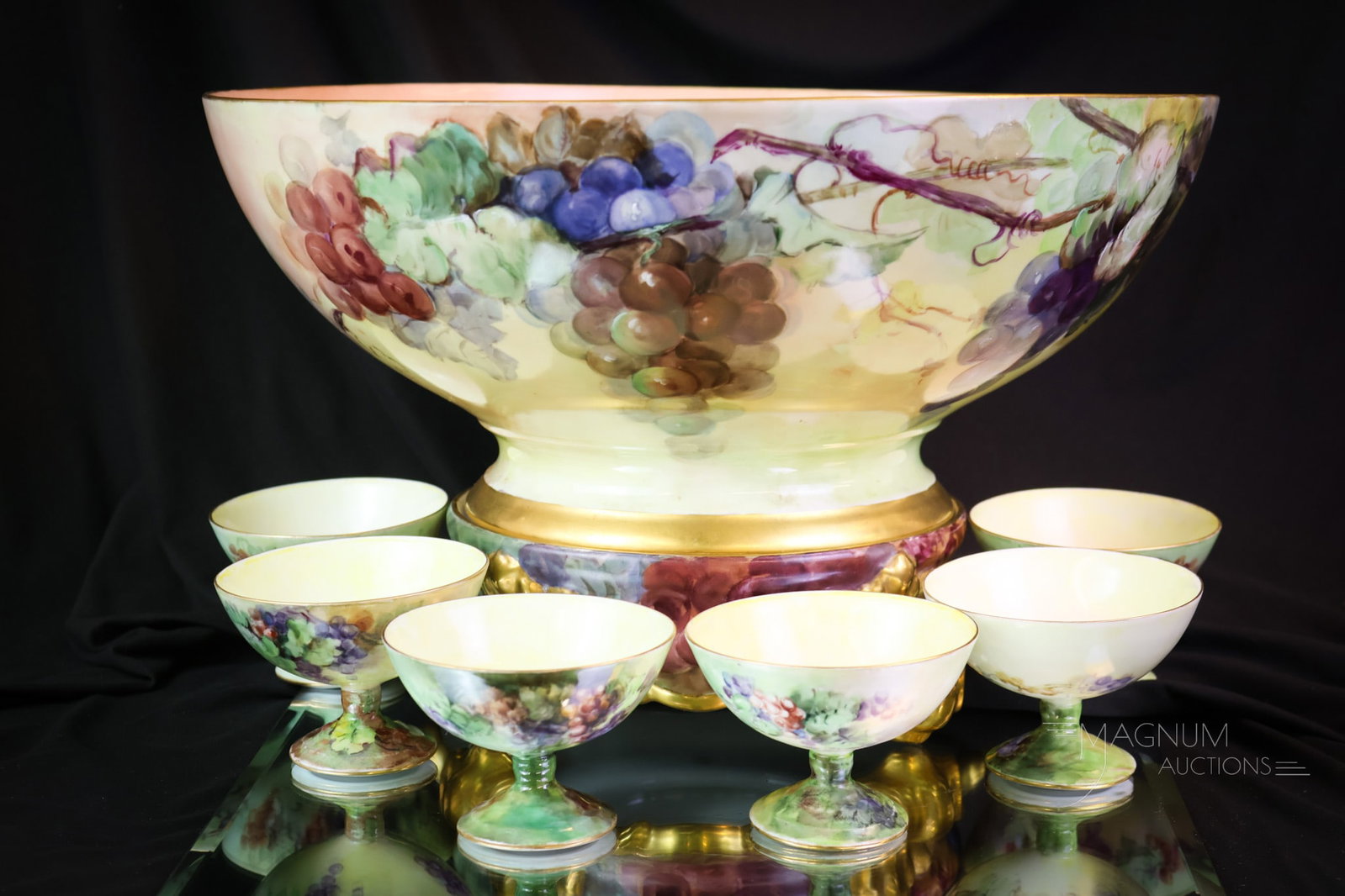 8 pc Set Limoges France Grapes & Gold Punch Set: A wonderful offering of a complete set of Limoges, France hand hand-painted porcelain. This set consists of the master bowl, six pedestal-stemmed cups, and the plinth for the bowl. The set is gracious