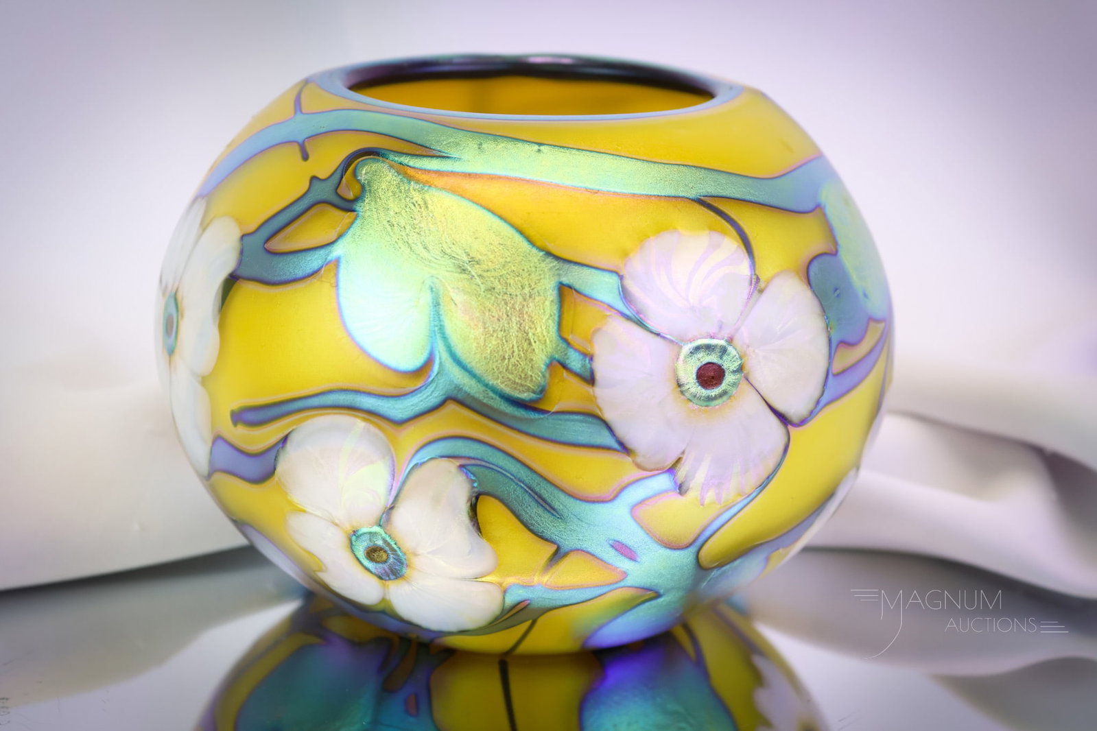 Signed Charles Lotton 1994 Multiflora Rose Bowl Vase: A striking find in signed Charles Lotton art glass. This rose bowl vase is dated 1994. It features a vivid yellow ground with blue iridescent designs and Dogwood flowers in white. The vase measures 5"