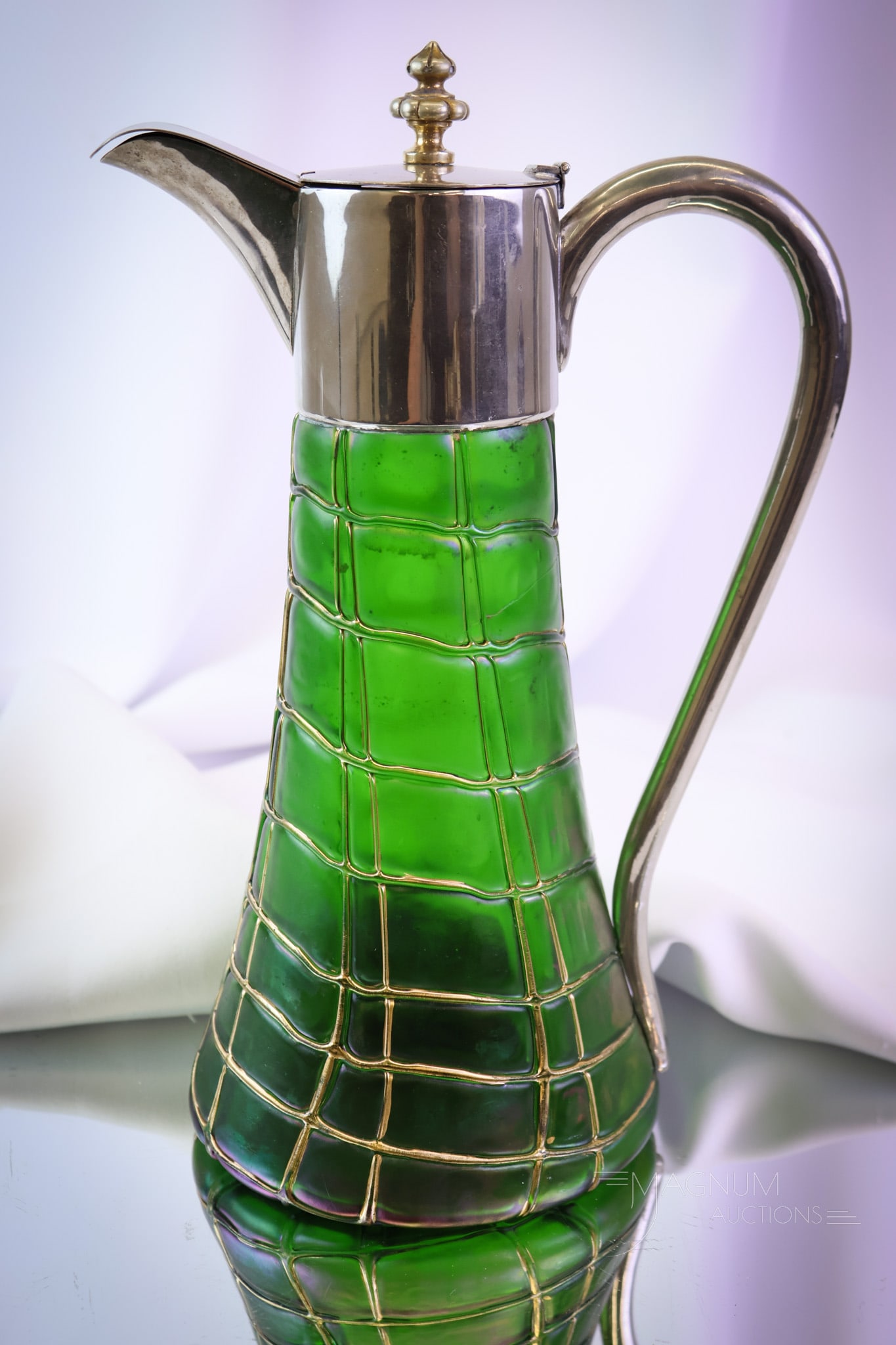 Palme Koenig Green Iridescent Art Glass Silverplate Claret Pitcher: A wonderful find in Palme Koenig art glass and silverplate. This claret pitcher is in green iridescent glass with random threading. The piece is completed by a metal top and handle. It measures 11 " t