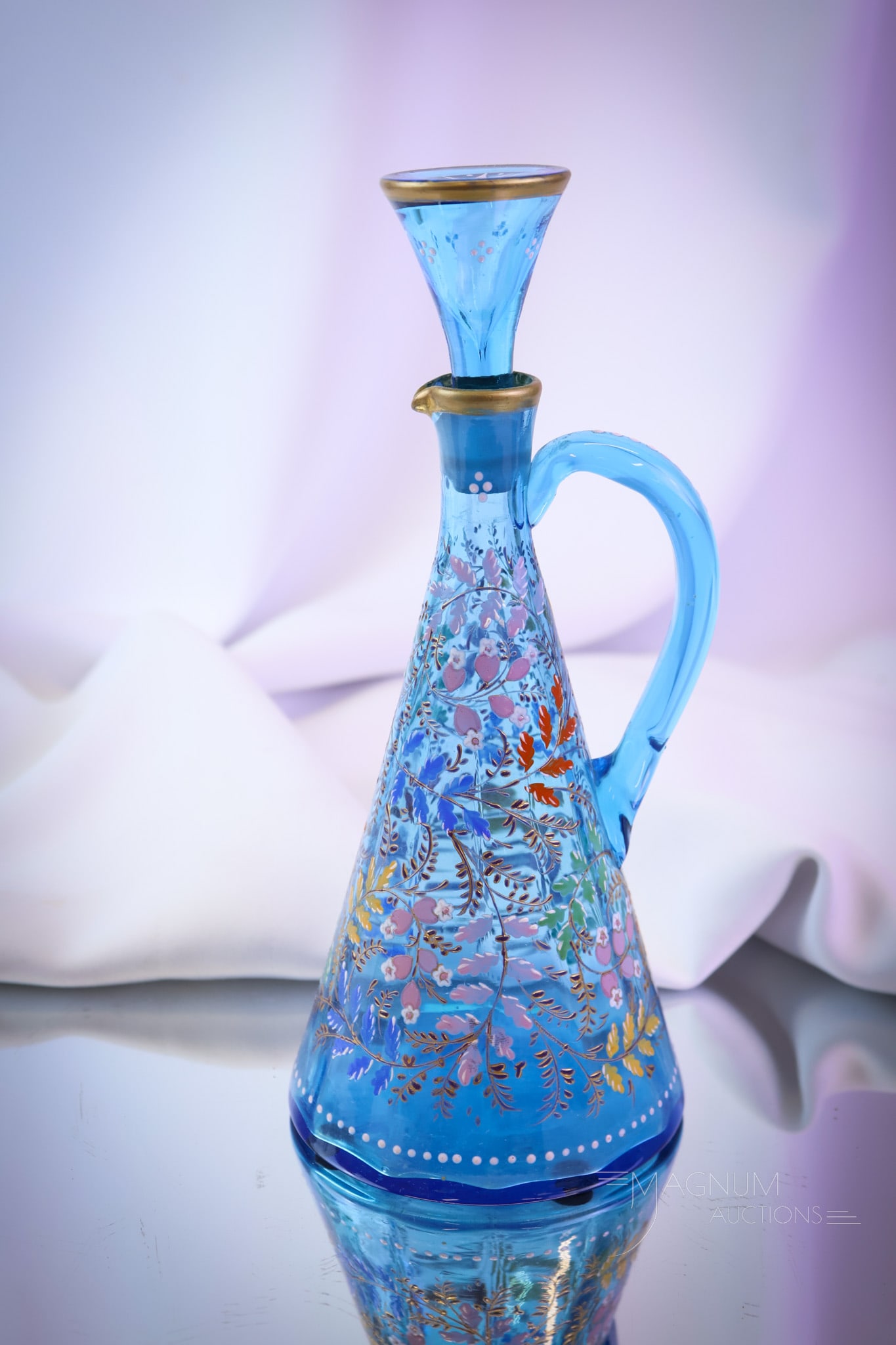 A Moser Blue Enameled Victorian Glass TeePee Cruet: Lovely and colorful enameled decoration abounds on this Moser cruet. It is complete with the original stopper. It measures 9" tall. SHIPPING NOTICE: If you choose not to utilize the LiveAuctioneers Li