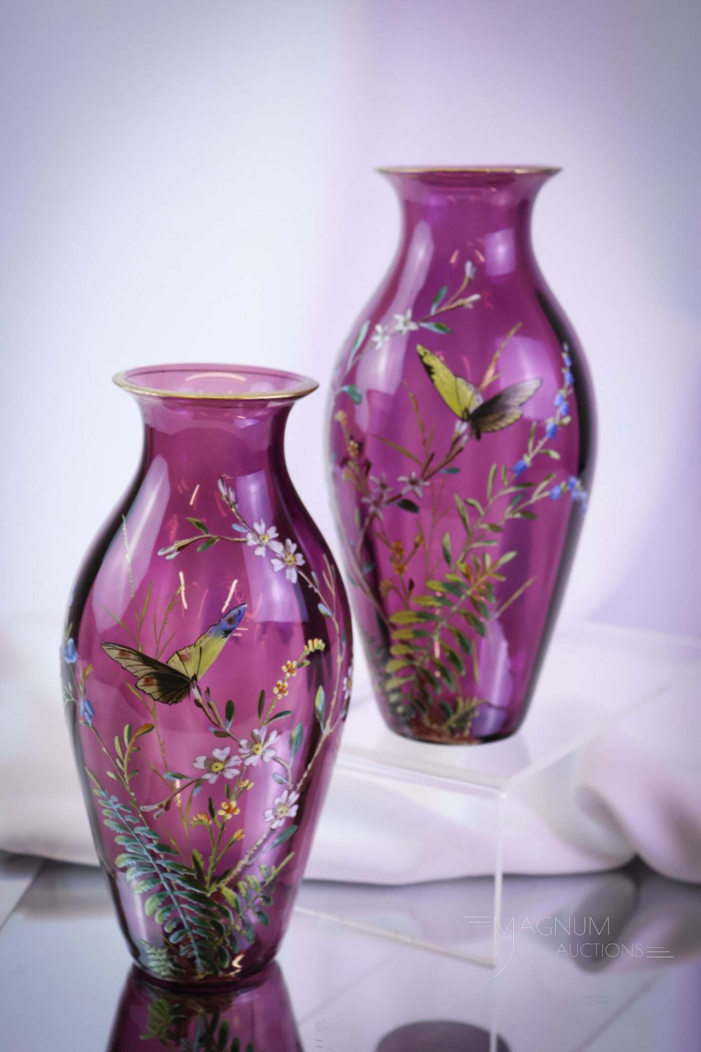Pair Victorian Bohemian Enameled Amethyst Glass Mantle Vases: A vivid amethyst pair of Victorian enameled glass mantle vases. Each has flowering botanicals and butterflies. Each measures 8" tall. SHIPPING NOTICE: If you choose not to utilize the LiveAuctioneers 