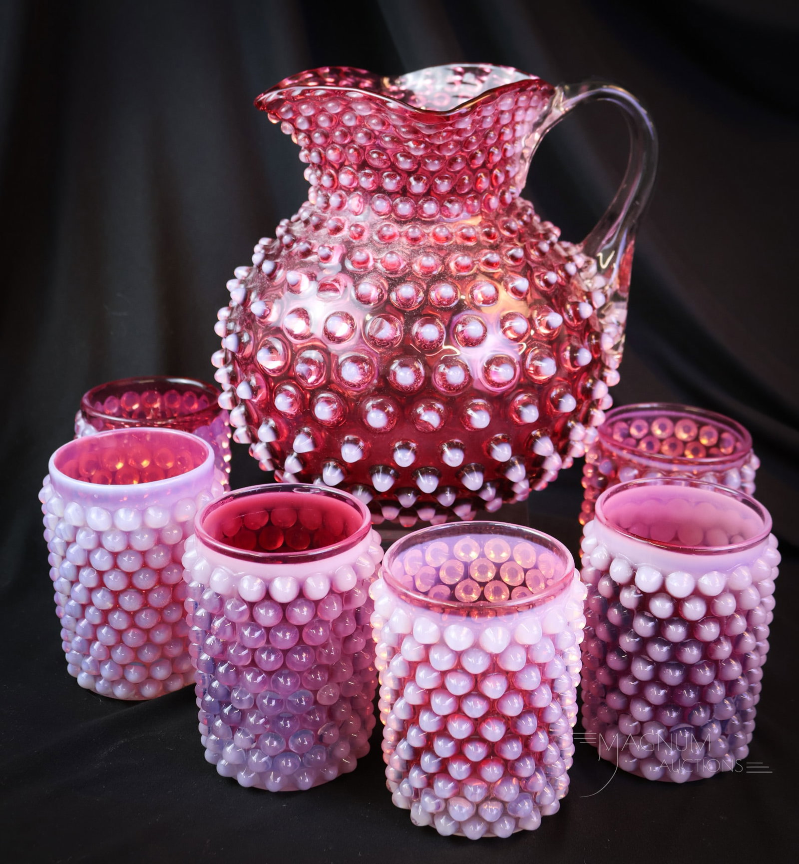 7 pc Hobbs Cranberry Opalescent Victorian Glass Water Set: A nice find in Victorian Hobbs glass. This is a Hobnail pattern water set in cranberry opalescent. This set includes a pitcher and six tumblers. The tallest of the set measures 7 1/2". Two chipped hob