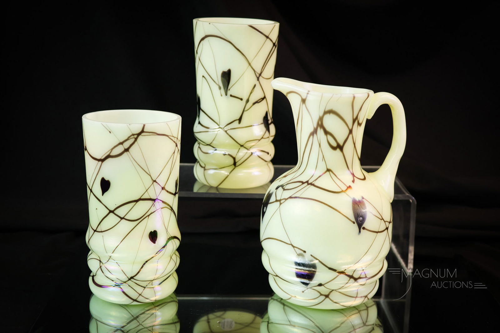 3 pc Lot Fenton Uranium Custard Hanging Heart Art Glass: Three selections in Fenton uranium-rich art glass. Each piece is marked "Fenton 1976."Each piece has a hanging heart decoration. The lot is comprised by a pitcher and two tumblers. The tallest measure