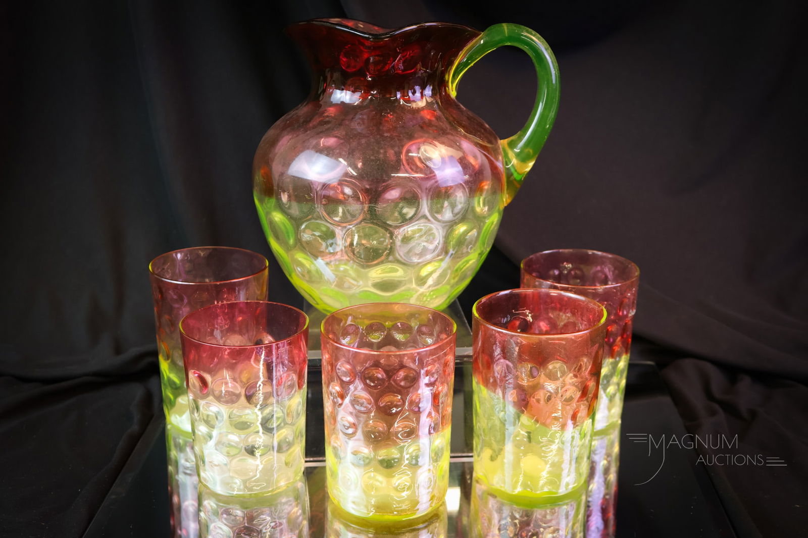 6 pc Hobbs Cranberry Uranium Vaseline Victorian Glass Water Set: A beautiful set in Hobbs cranberry to vaseline Rubina Verde Inverted Thumprint pattern. The set consists of a pitcher and five tumblers. The tallest measures 7". One tumbler exhibits a rim chip. SHIPP