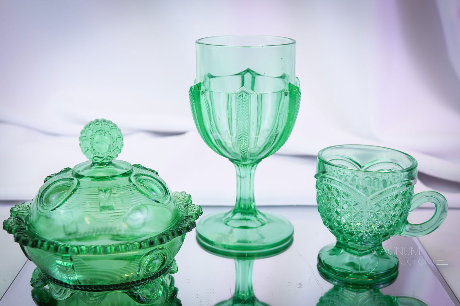 3 pc Lot Green Victorian Greentown Glass: Three lovely finds in Victorian Greentown green glass articles. This lot includes a Herringbone Buttress water goblet. An Austrian pattern mug. The final piece is a Dewey pattern covered butter dish.