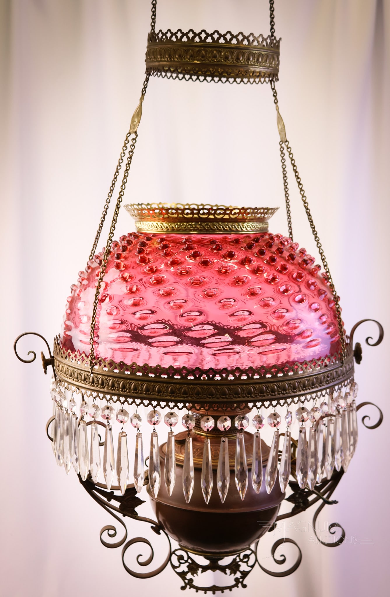 Cranberry Glass Hobnail Victorian Hanging Parlor Oil Lamp: A collection-enhancing Victorian cranberry glass Hobnail pattern hanging parlor oil lamp. This lamp has a brilliant cranberry glass shade. The lamp retains the original motor. Clear prisms adorn the f