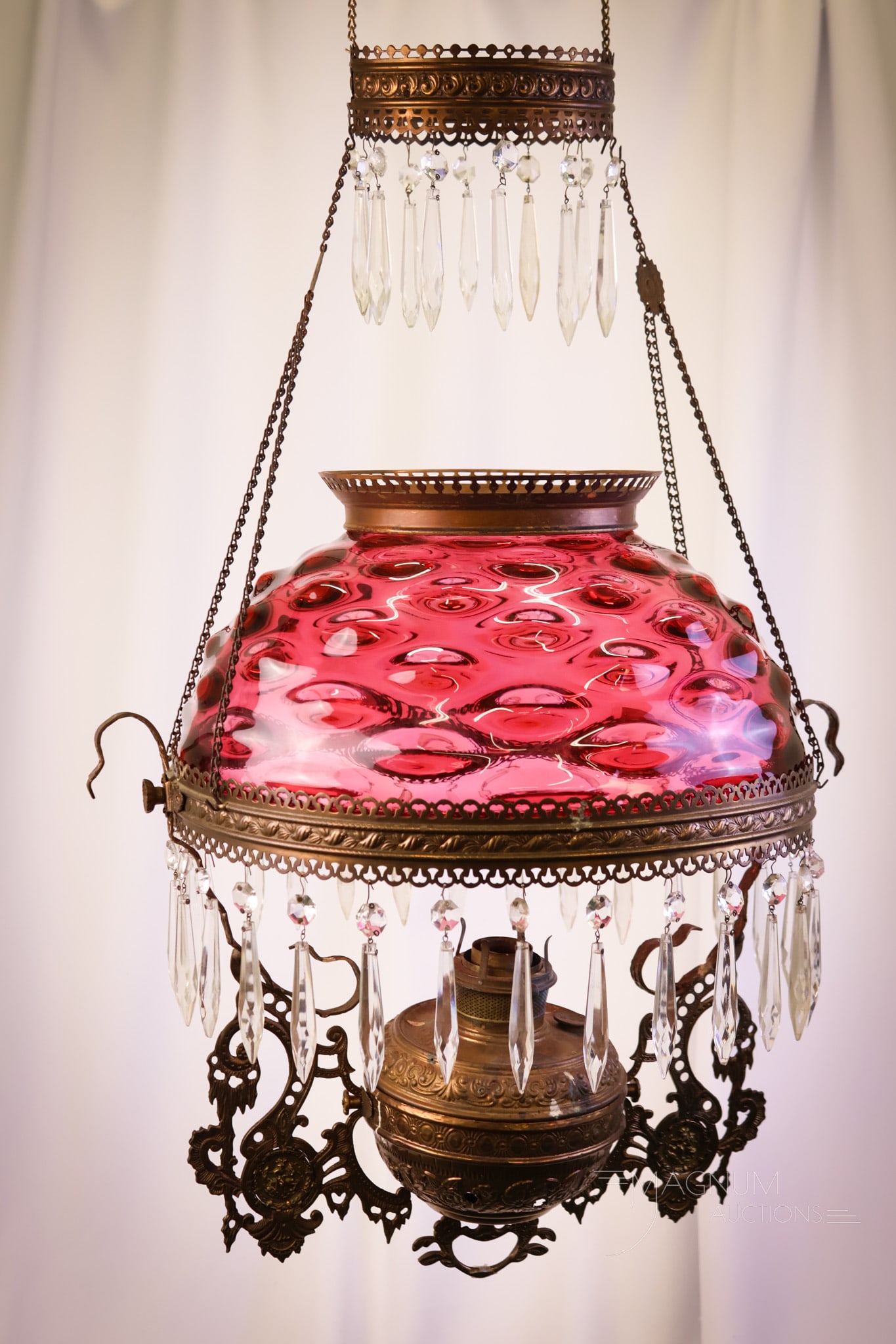 Victorian Ruby Glass Bradley & Hubbard Hanging Parlor Oil Lamp: An attractive Victorian ruby glass Bullseye pattern hanging parlor oil lamp. The frame is a Bradley & Hubbard. The lamp remains oil and retains it motor. The lamp measures 40" long and 18" wide. SHIPP