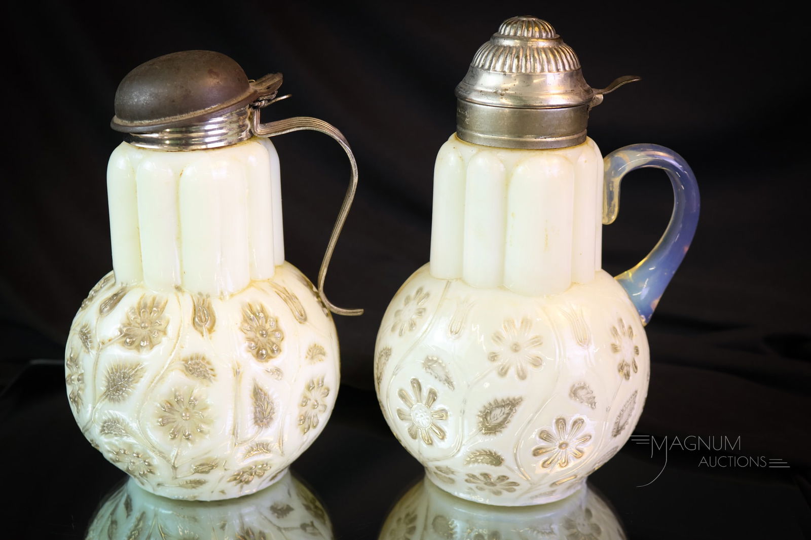 2 pc Lot Victorian Findlay Onyx Glass Syrup Pitchers: Two unique examples of Victorian Findlay Onyx syrup pitchers. One has an applied glass handle. The other has a metal handle attached to the lid. This one the lid sits ascew. The tallest measures 7". S