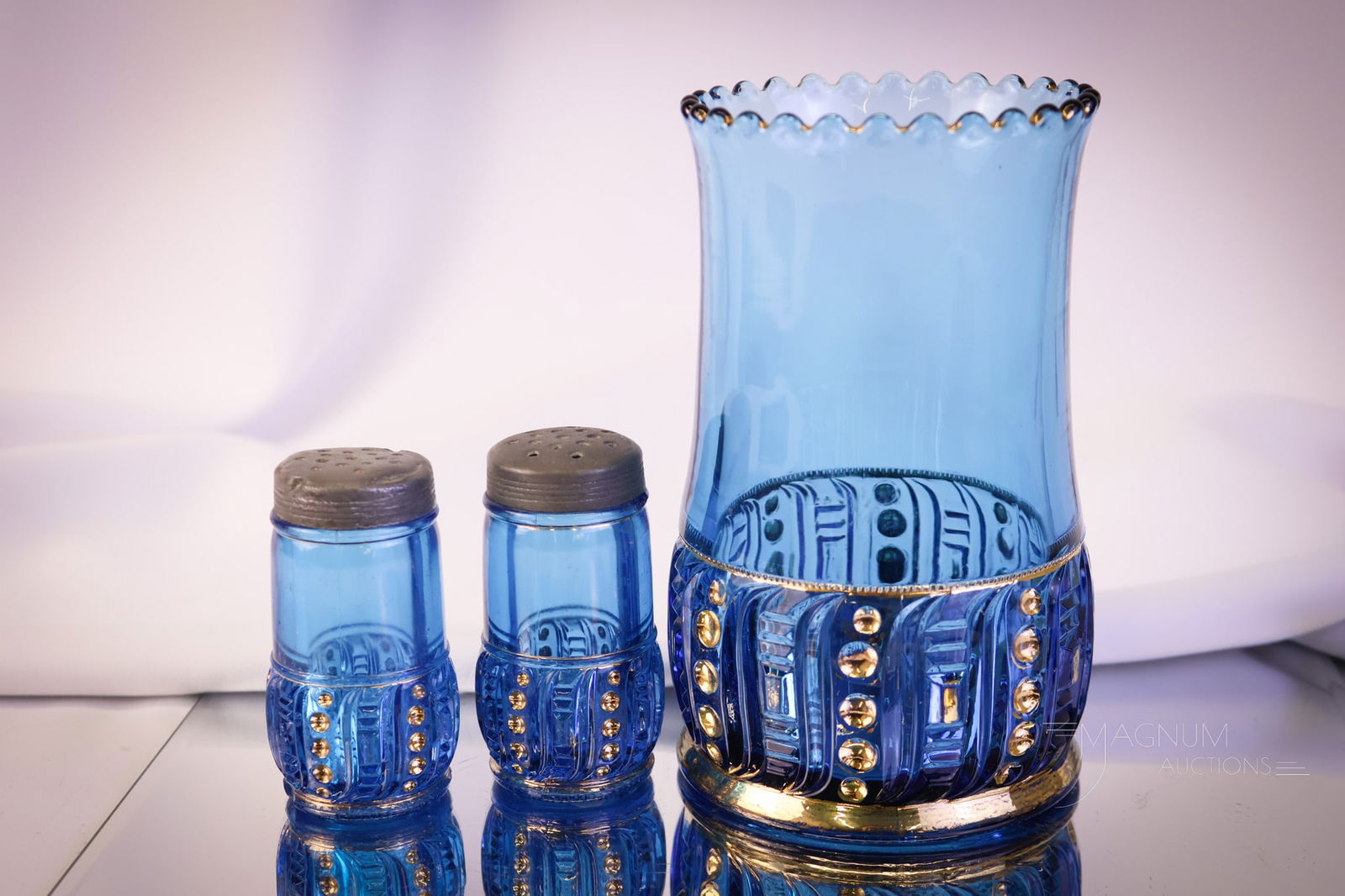 3 pc Lot Riverside Blue & Gold Seedpod Victorian Glass: Three fine examples of the Riverside Seedpod pattern in blue with gold decoration. This lot consists of a celery vase and a pair of shaklers. The tallest measures 6 1/4". Provenance: This item is fro