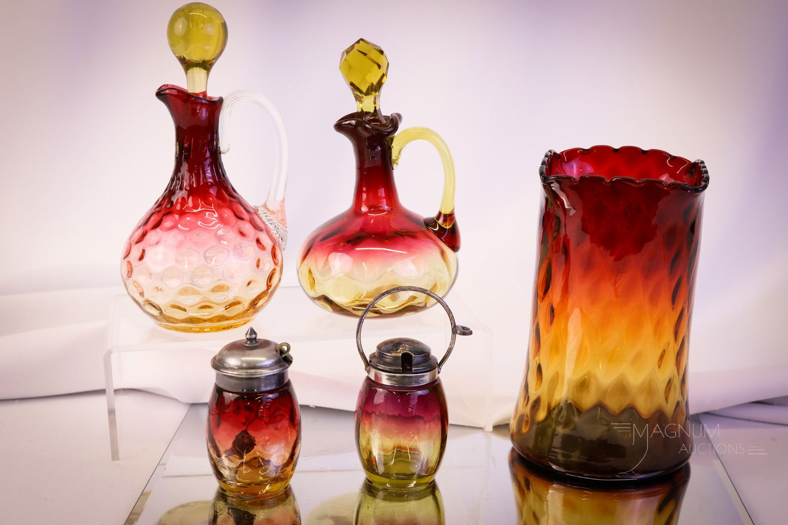 5 pc Lot Victorian Amberina Glass: Five desirable finds in Victorian amberina glass. This lot includes a Mt. Washington diamond-quilt celery vase. An Inverted Thumbprint cruet and mustard. Lastly, there is a contemporary cruet in the t