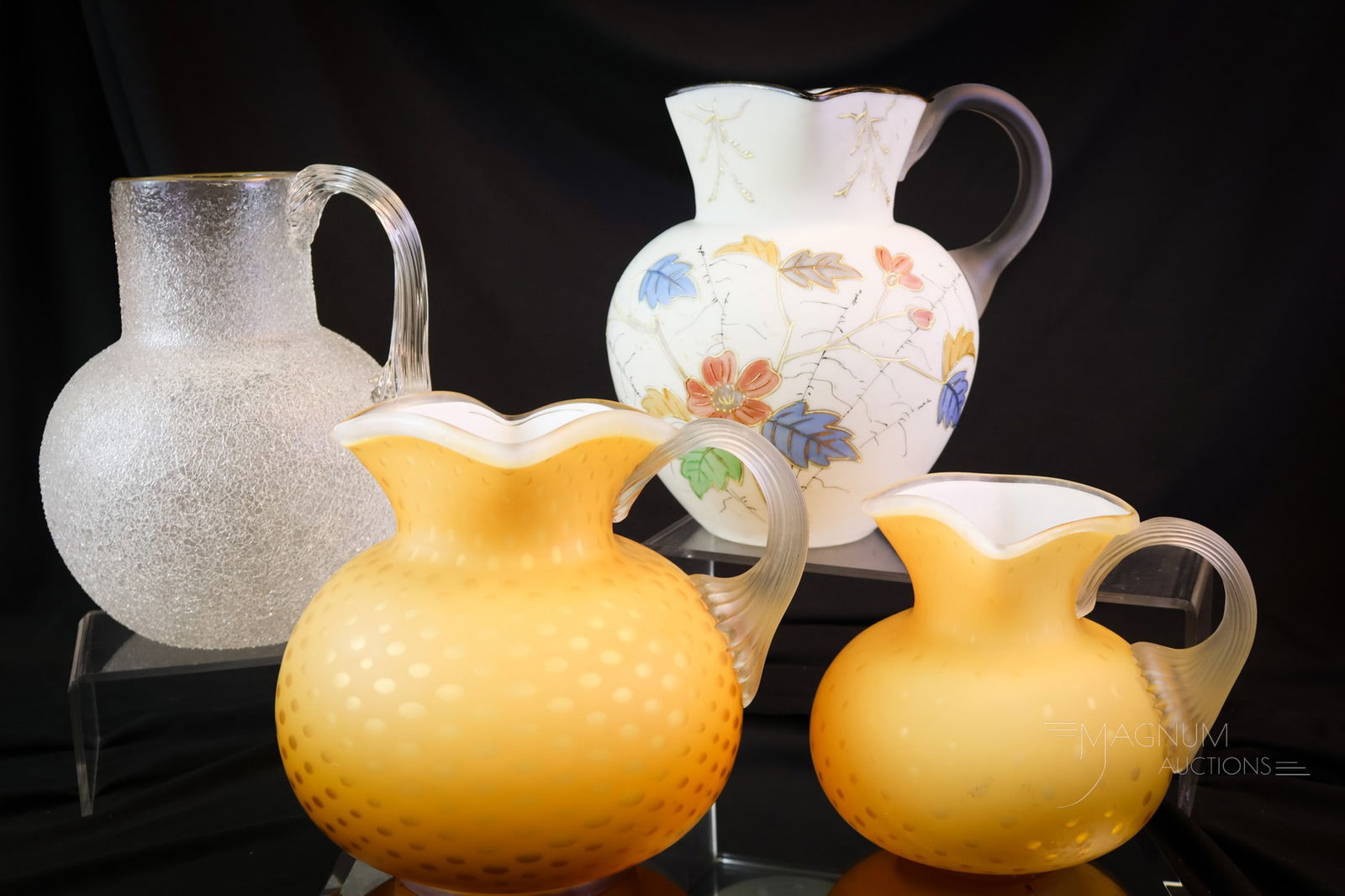 4 pc Lot Victorian Art Glass Water Pitcher: Four attractive and collectible Victorian art glass water pitchers. This lot includes a clear overshot glass example with a gold rim. A decorated, attributed to Wavecrest example. Lastly, there are tw