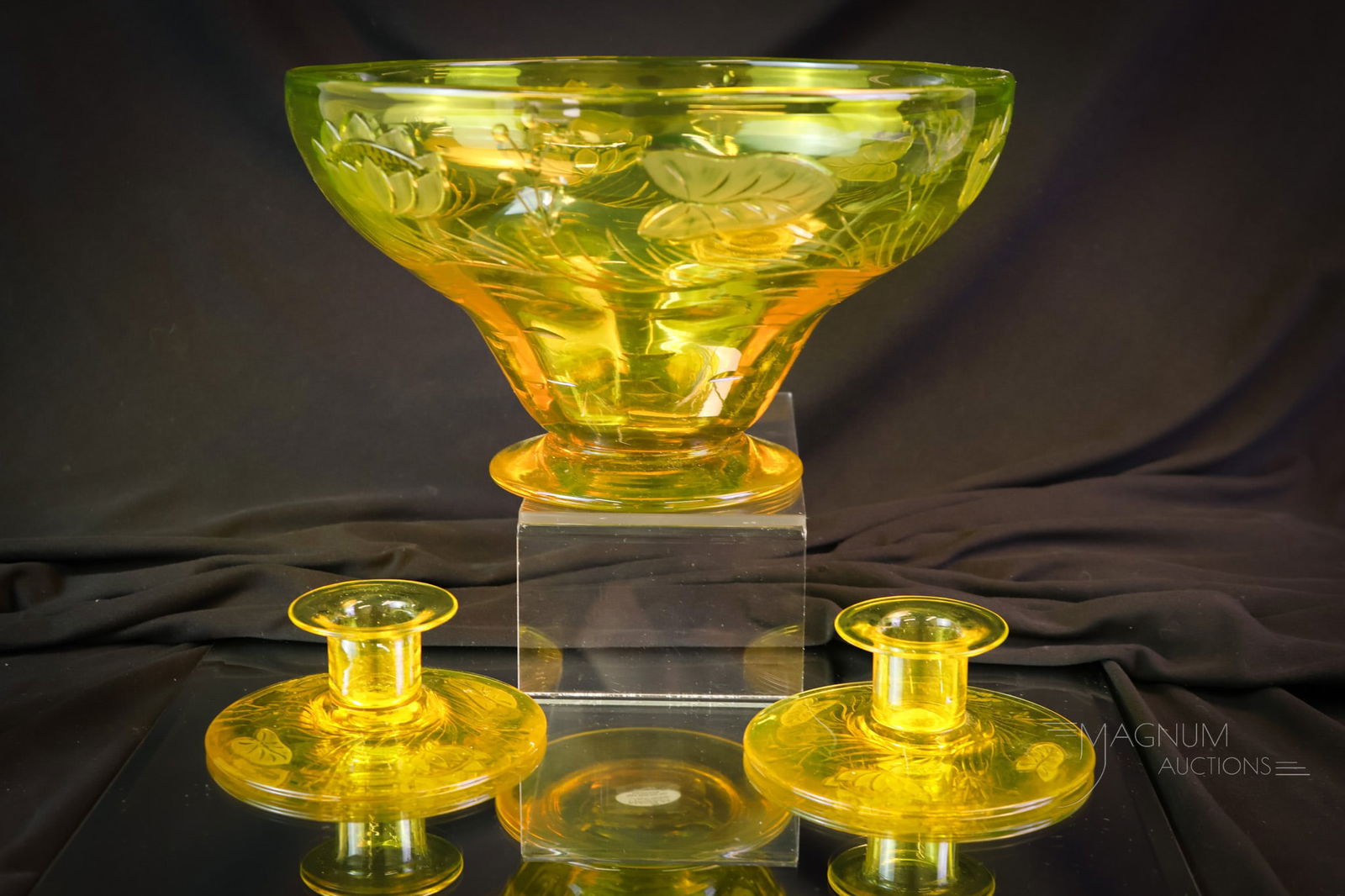 3 pc Lot Vaseline Uranium Engraved Glass Console Set: A fine engraved console set in the manner of Pairpoint. This set includes two candle holders and a bowl. Each piece with a water lily cutting. The tallest measures 5 3/4". The set glows brightly under