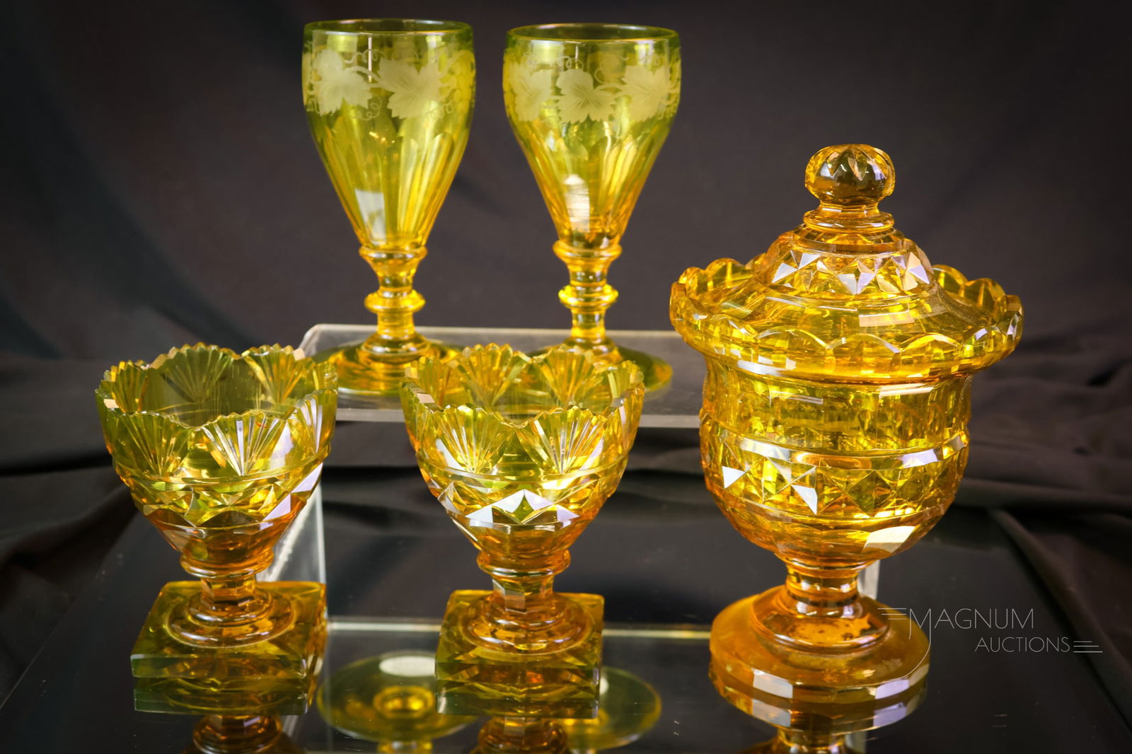 5 pc Lot Bohemian Amber Uranium Vaseline Cut Engraved Glass: Five delights in uranium-rich amber vaseline uranium glass from Bohemian glass makers. This lot includes a covered pokal and two egg cups along with two grape etched cordials. The tallest measures 6 1