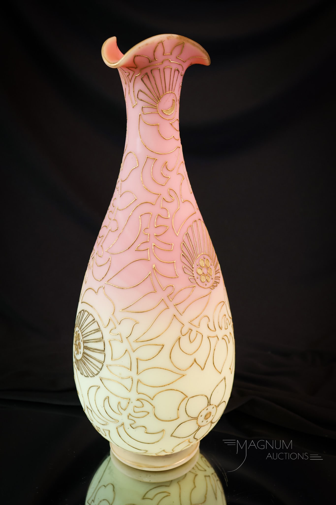 Mt. Washington Burmese Art Glass 12" Gilt Vase: A beautiful example of the fine pieces of glass that Mt. Washington Art Glass Company made. This vase measures 12" tall and 4 1/2" wide. It is decorated around the body with gilt scrollwork. This vase