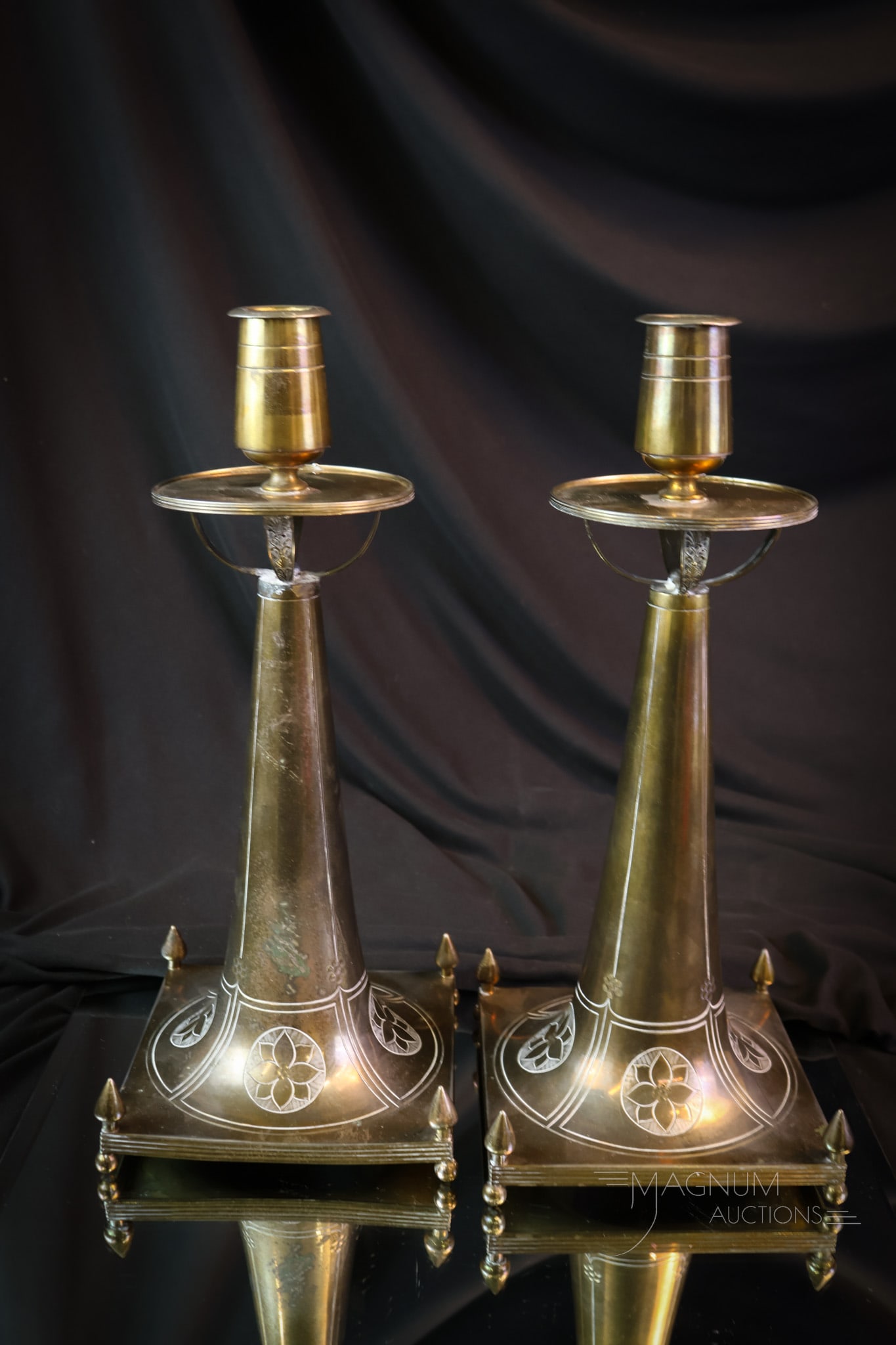 Pair Antique Arts & Crafts Brass Incised Candlesticks: A beautiful pair of Arts & Crafts period antique brass candlesticks. This pair features an incised design of a floral pattern. Each has removable candle cups. Each measures 12" tall and 5 1/4" wide. S