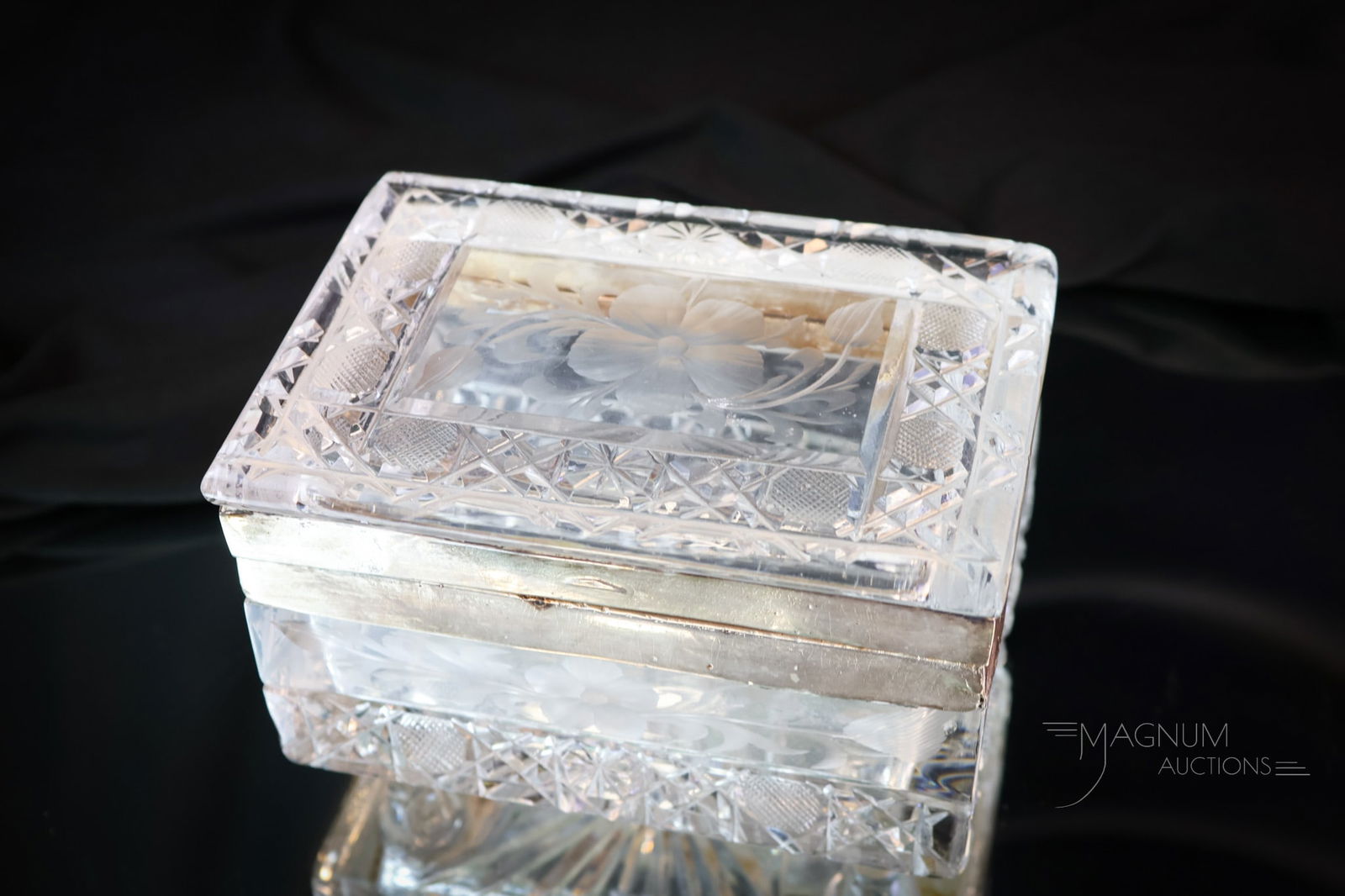 Cut Crystal Jewelry casket: A rectangular cut crystal jewelry casket with silverplate banding. This piece is in a button & crosshatch pattern with engraved flowers. The casket sits atop four little feet. The piece measures 3 1/2