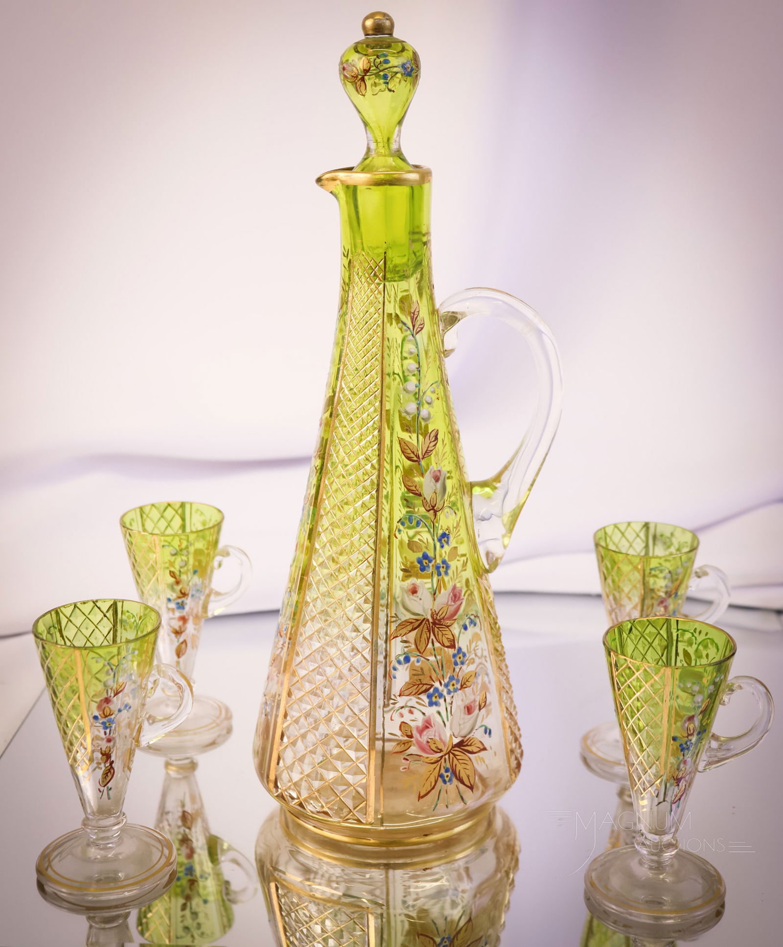 5 pc Moser Cut and Enameled Green Art Glass Decanter Set: A beautiful offering of a five-piece set of green to clear Moser attributed art glass. This set features the decanter and four cordials. The pieces feature alternating diamond-cut panels and enameled