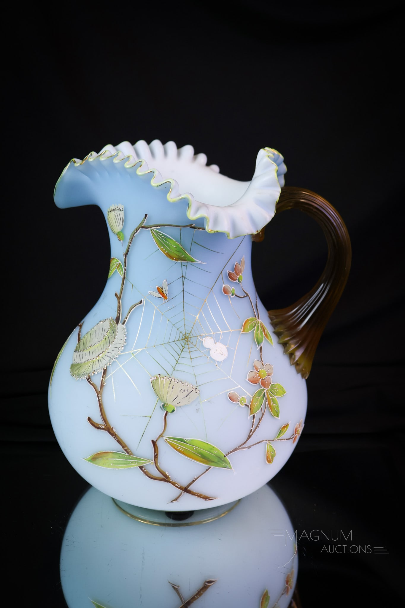 Victorian Spider & Web Enameled Satin Art Glass Water Pitcher: A nice find in a cased satin Victorian art glass water pitcher. This pitcher has an applied amber handle. It features a decoration of a spider in a web and florals. The pitcher measures 9" tall. SHIPP