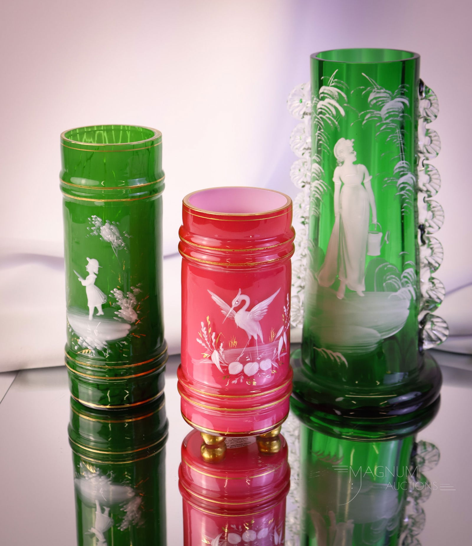3 pc Lot Mary Gregory Victorian Glass Vases: Three unique and decorative Victorian Mary Gregory decorated glass vases. One example is in emerald green The two remaining are pink cased glass with stork figures. The tallest measures 8".