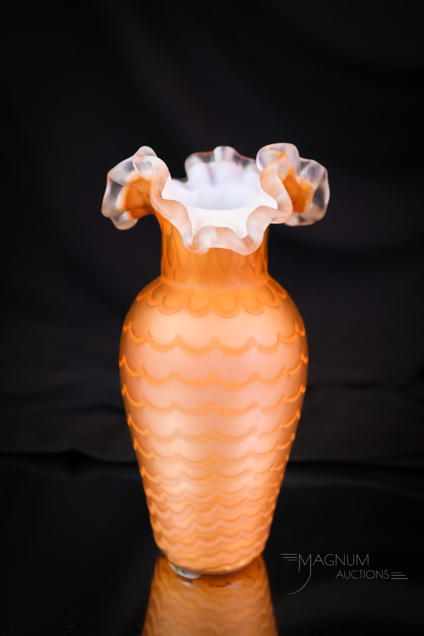Victorian Satin Mother of Pearl Drapery Orange Cabinet Vase: A petite Victorian cabinet vase in deep orange mother-of-pearl satin glass. This vase is in an unusual drapery pattern. The vase features a ruffled applied glass rim. This piece measures 6 1/2" tall.